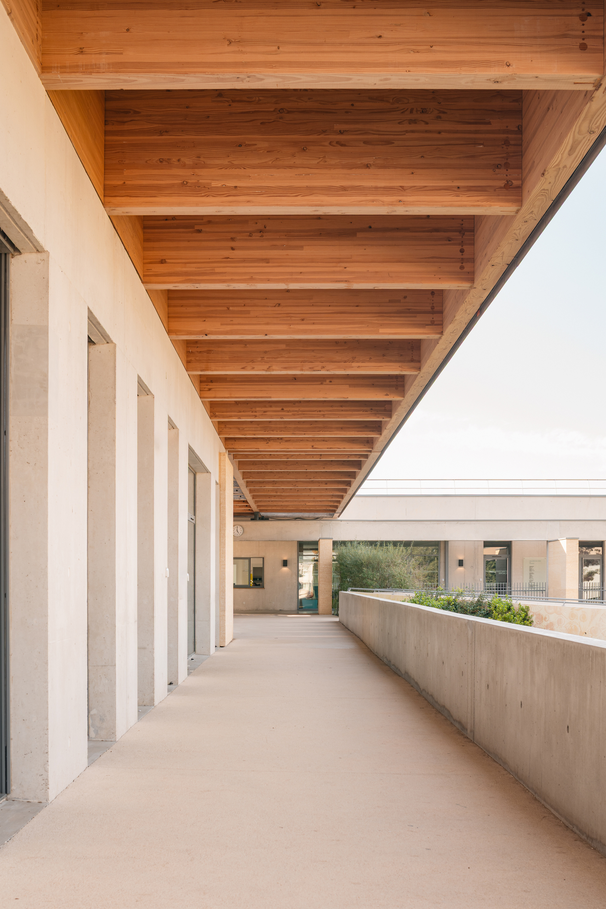 Covered walkway with exposed timber beams overhead and concrete planter along one edge
