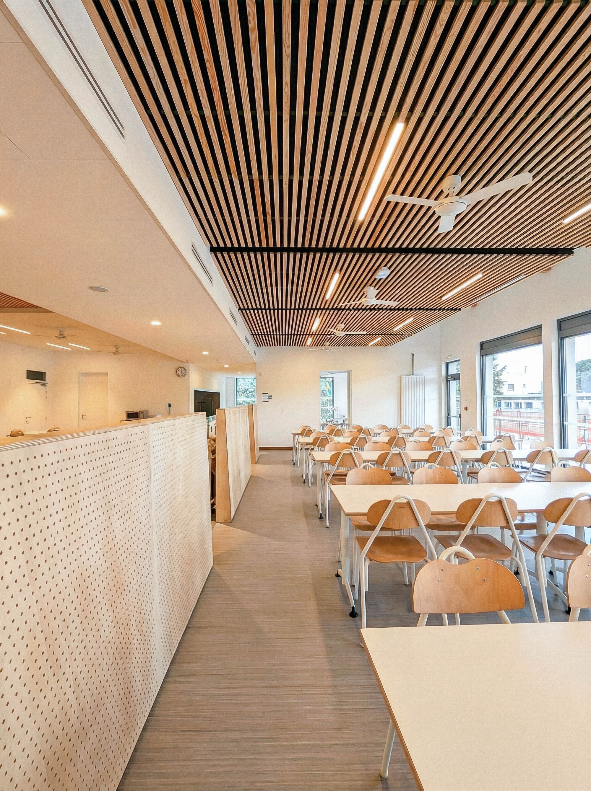 Slatted timber ceiling above a dining area with perforated white service counter along one wall
