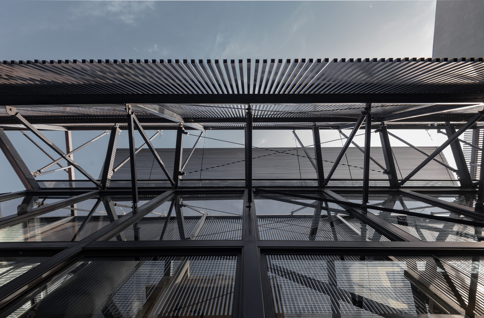Looking up at the exposed steel cross-bracing and corrugated metal ceiling louvers