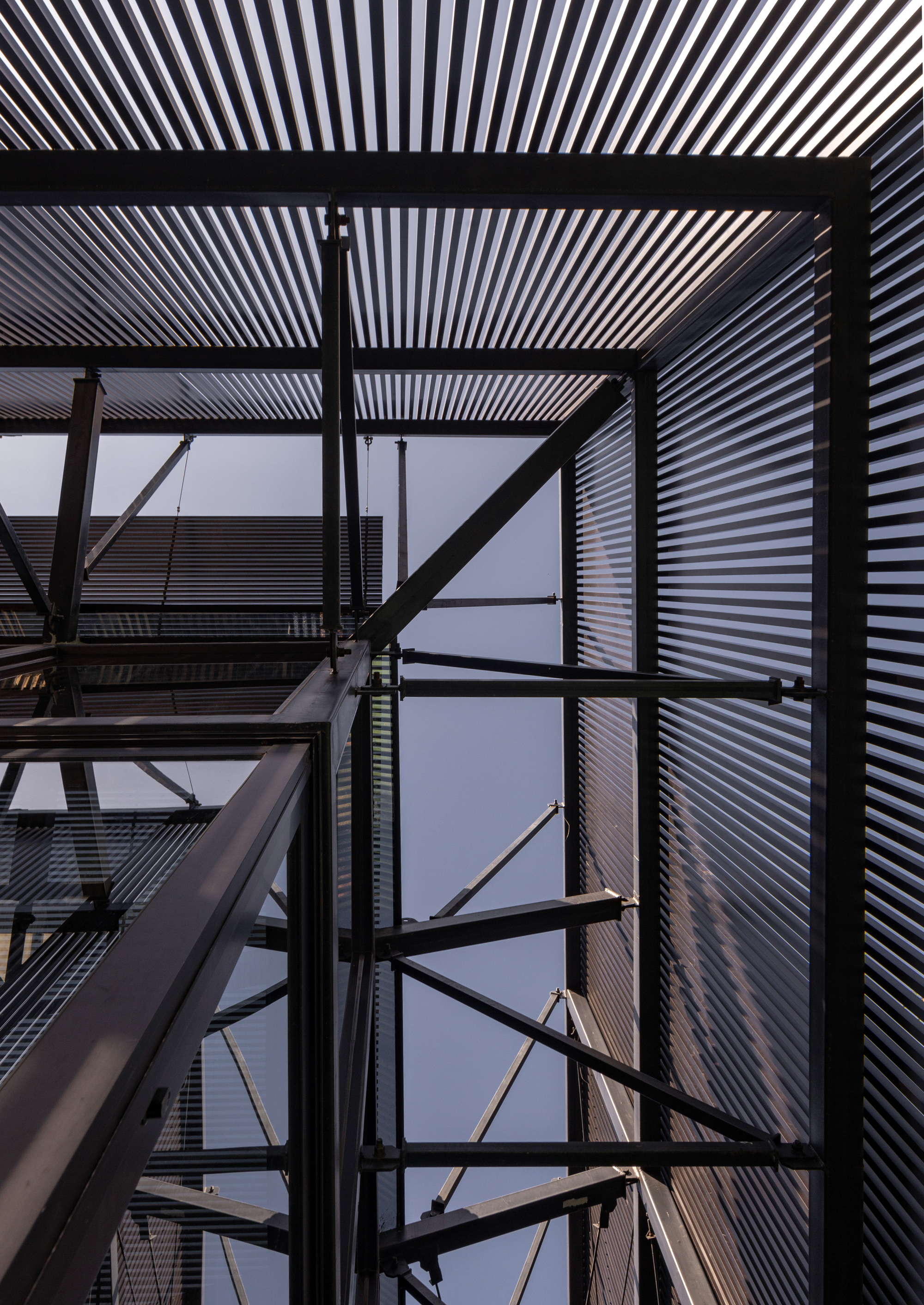 Looking up through the exposed steel frame structure with corrugated metal cladding against dusk sky