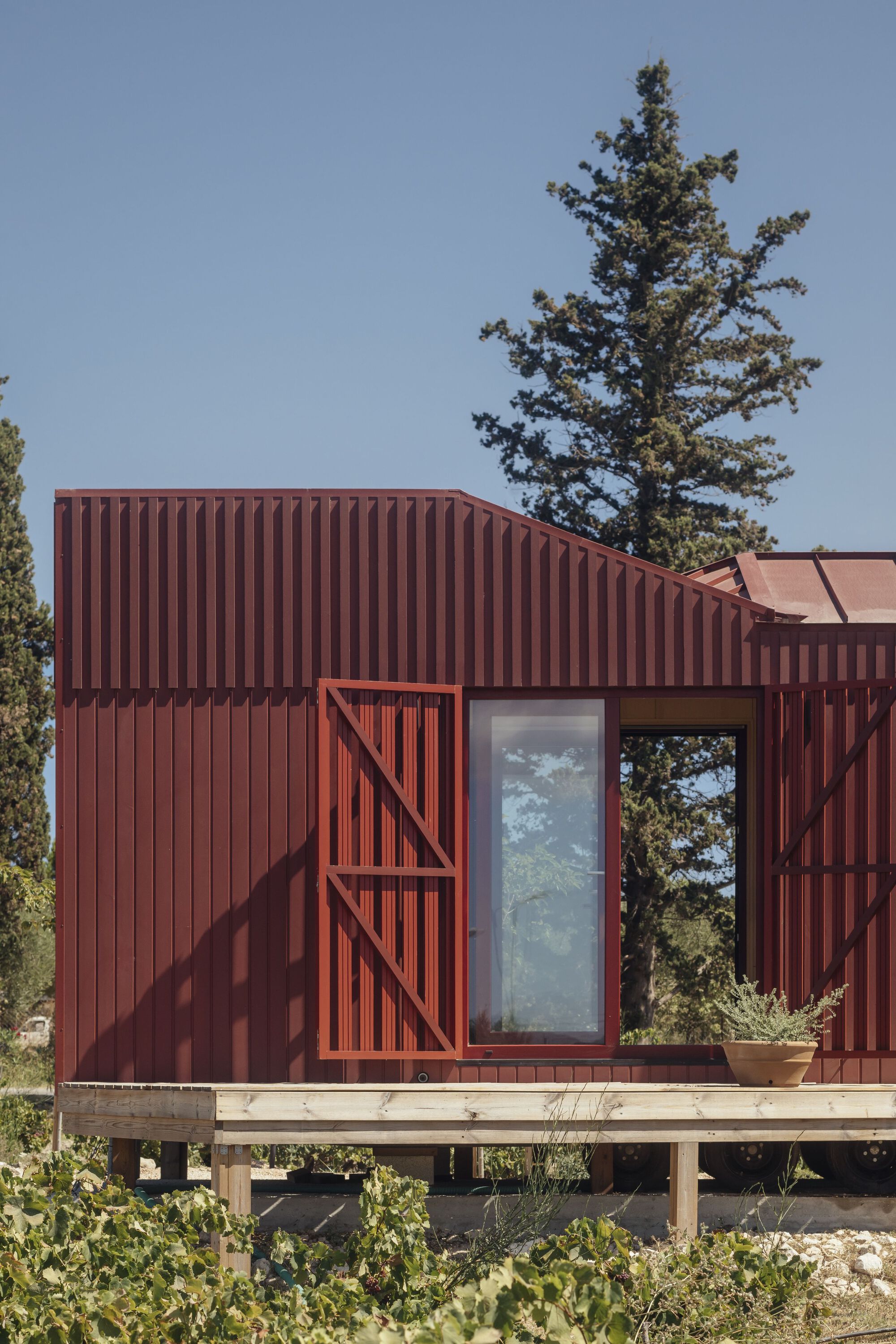Corner detail of the corrugated facade showing diagonal bracing and a tall vertical window