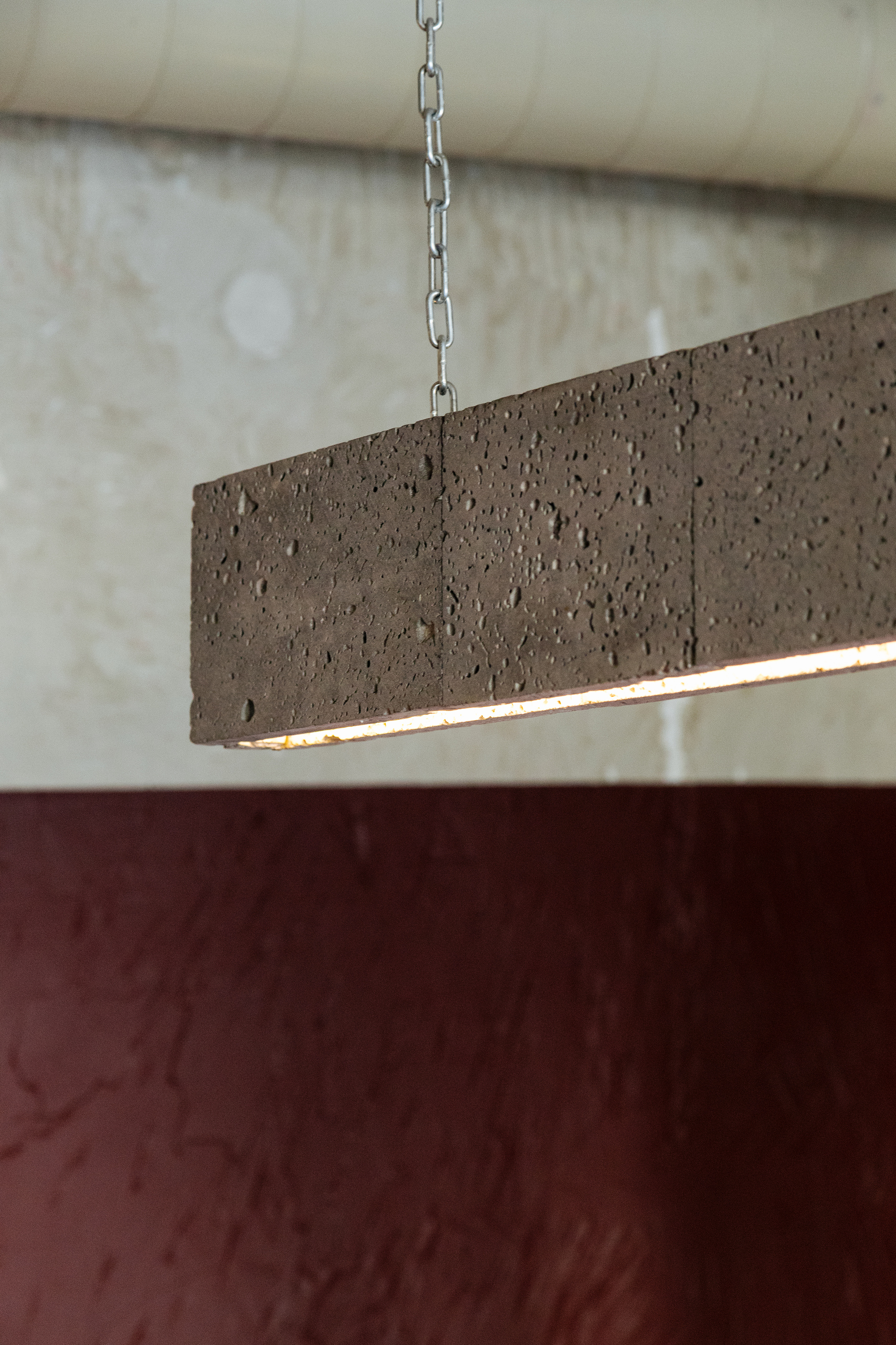 Suspended rectangular pendant light fixture in textured brown concrete with integrated linear illumination
