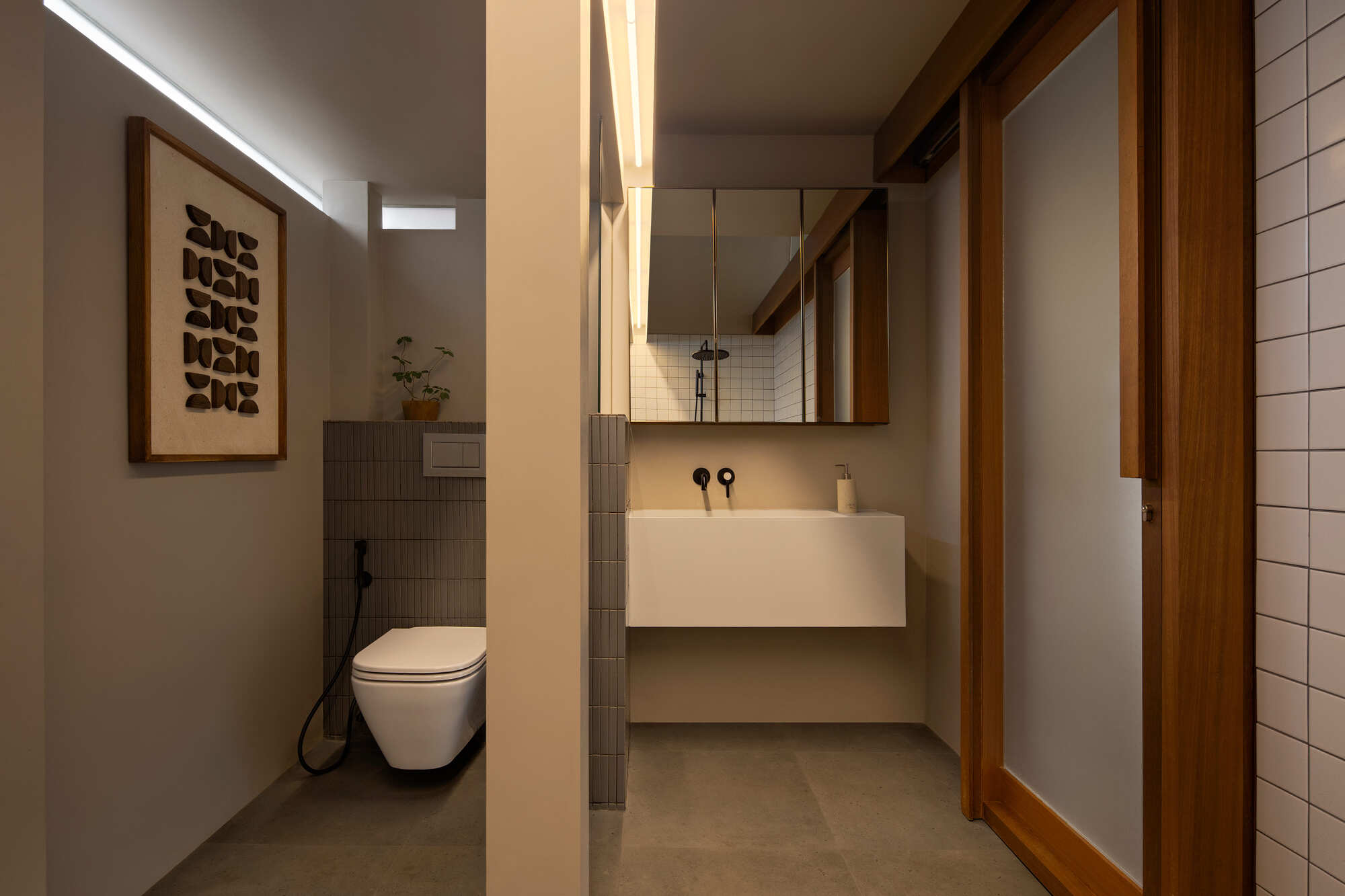 Bathroom with floating vanity, timber framed mirror and vertical strip lighting along the partition wall