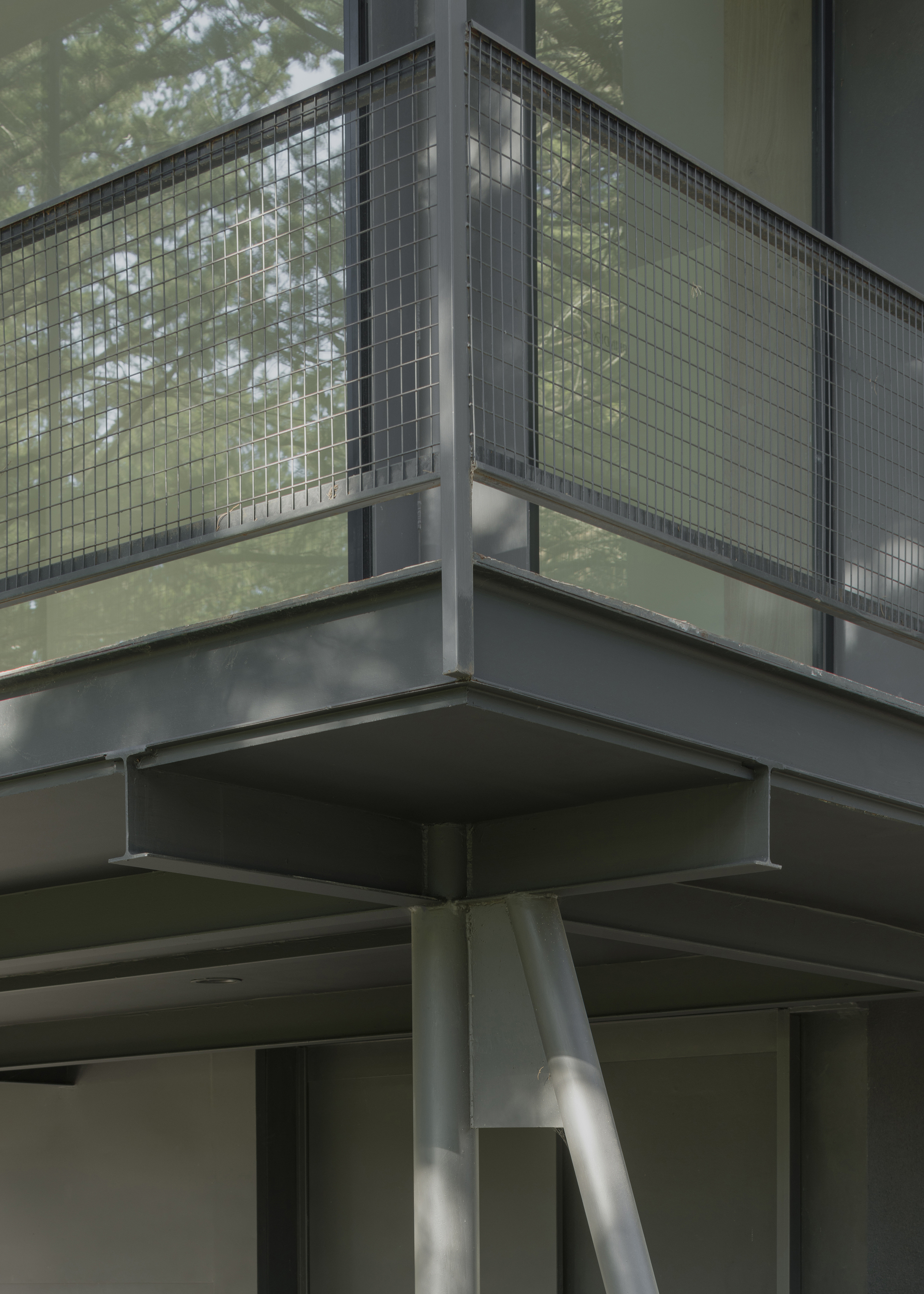 Detail of steel column junction supporting wire mesh balcony and cantilevered upper floor