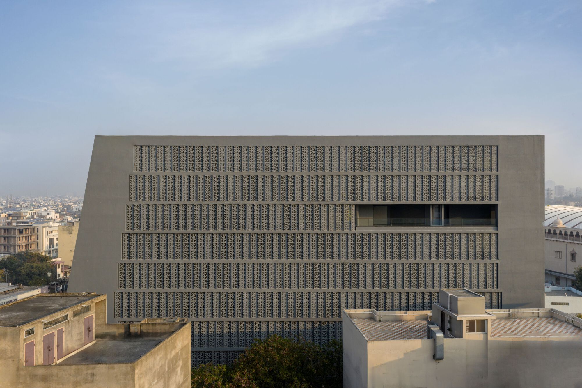 Head-on view of the gridded screen facade with rectangular window openings punctuating the pattern