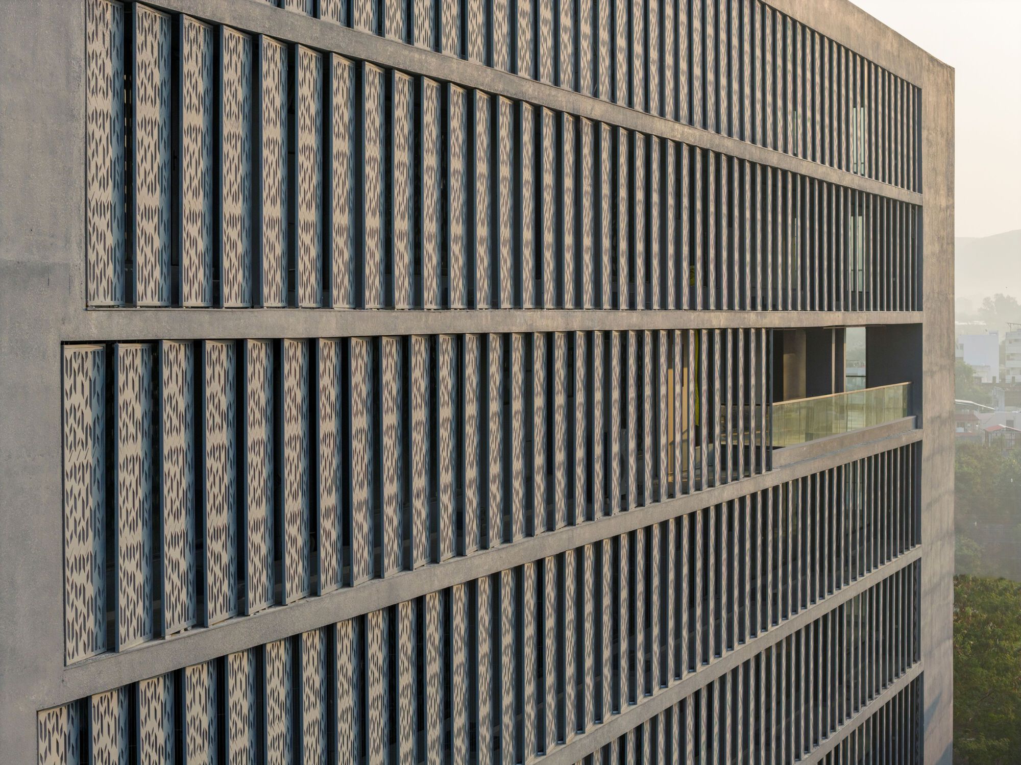 Facade detail showing alternating vertical concrete fins and patterned perforated brick panels between horizontal bands