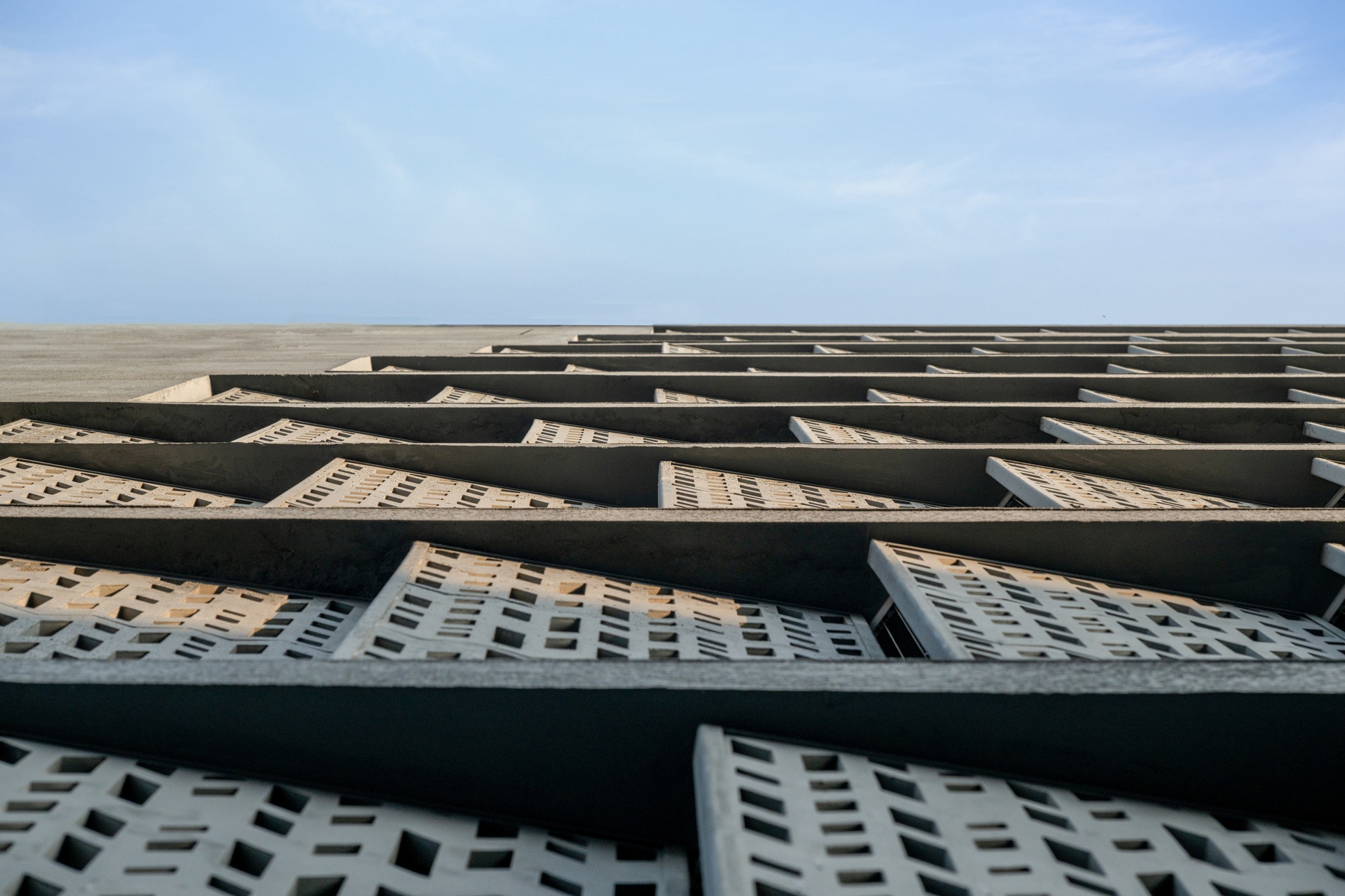 Looking up at the angled facade showing concrete diagonal bracing over perforated brick infill panels