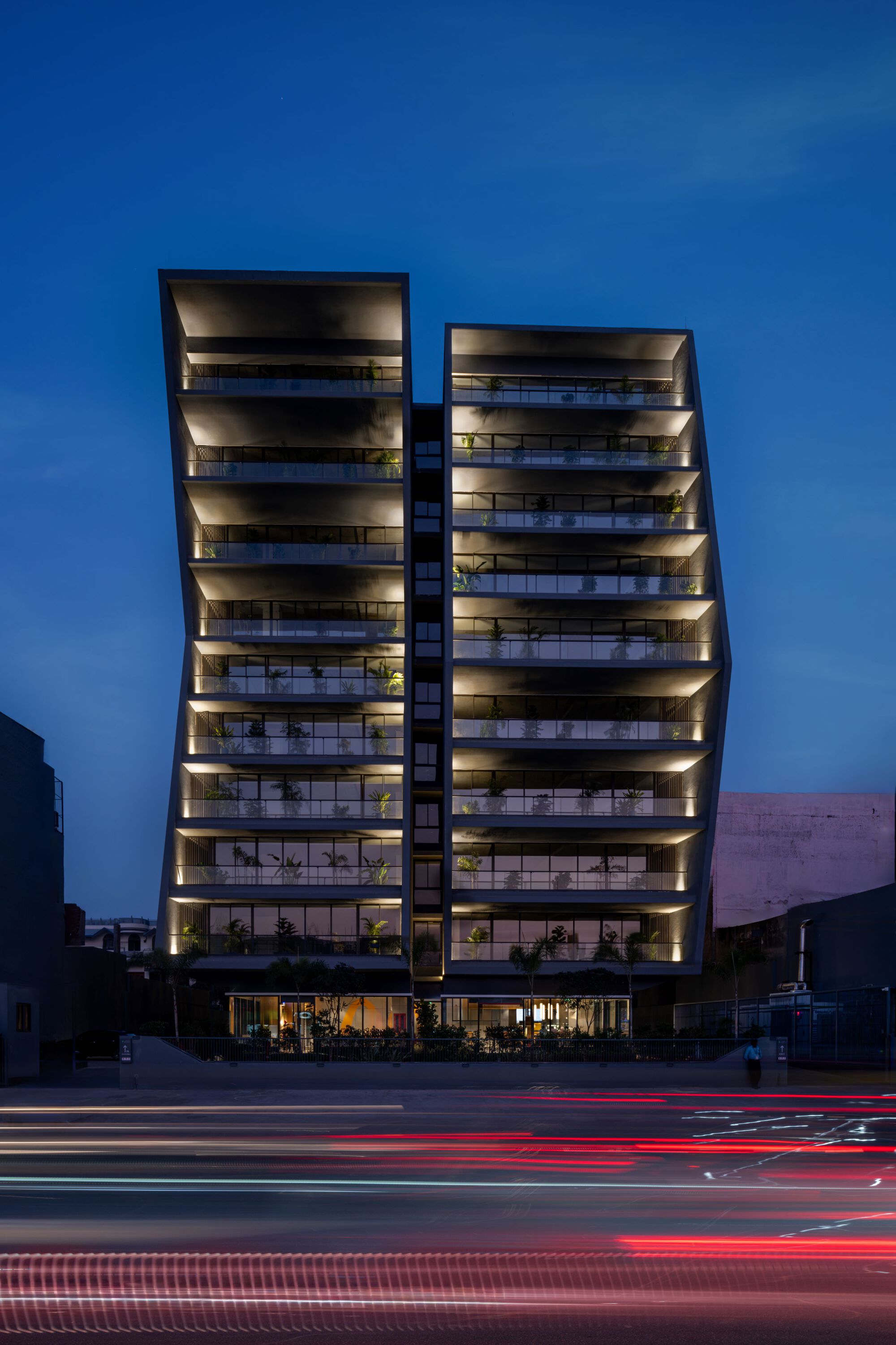 Twin-tower facade with illuminated floor plates and deep balconies at twilight