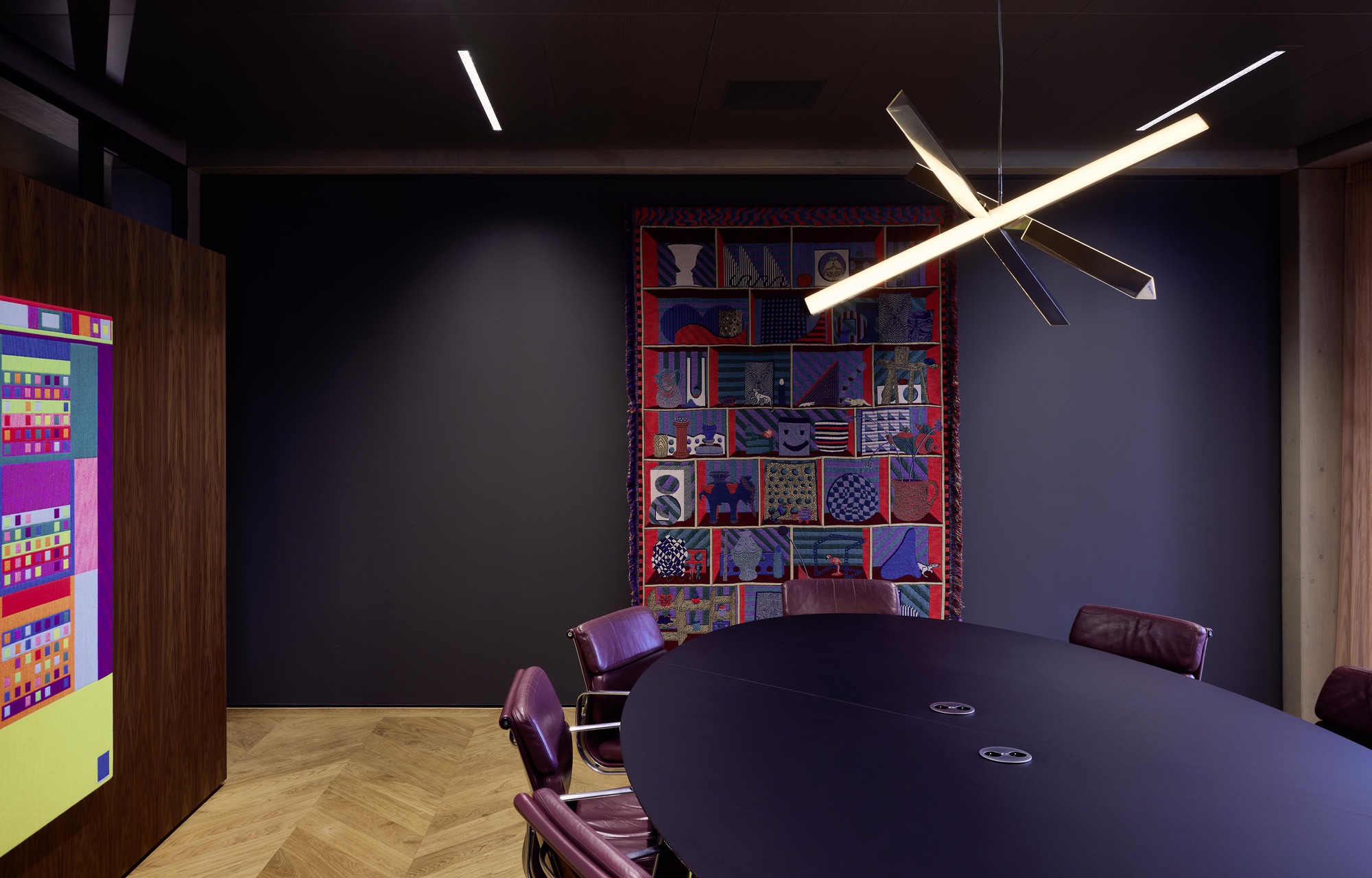 Conference room with dark walls and a suspended linear light fixture above a round table