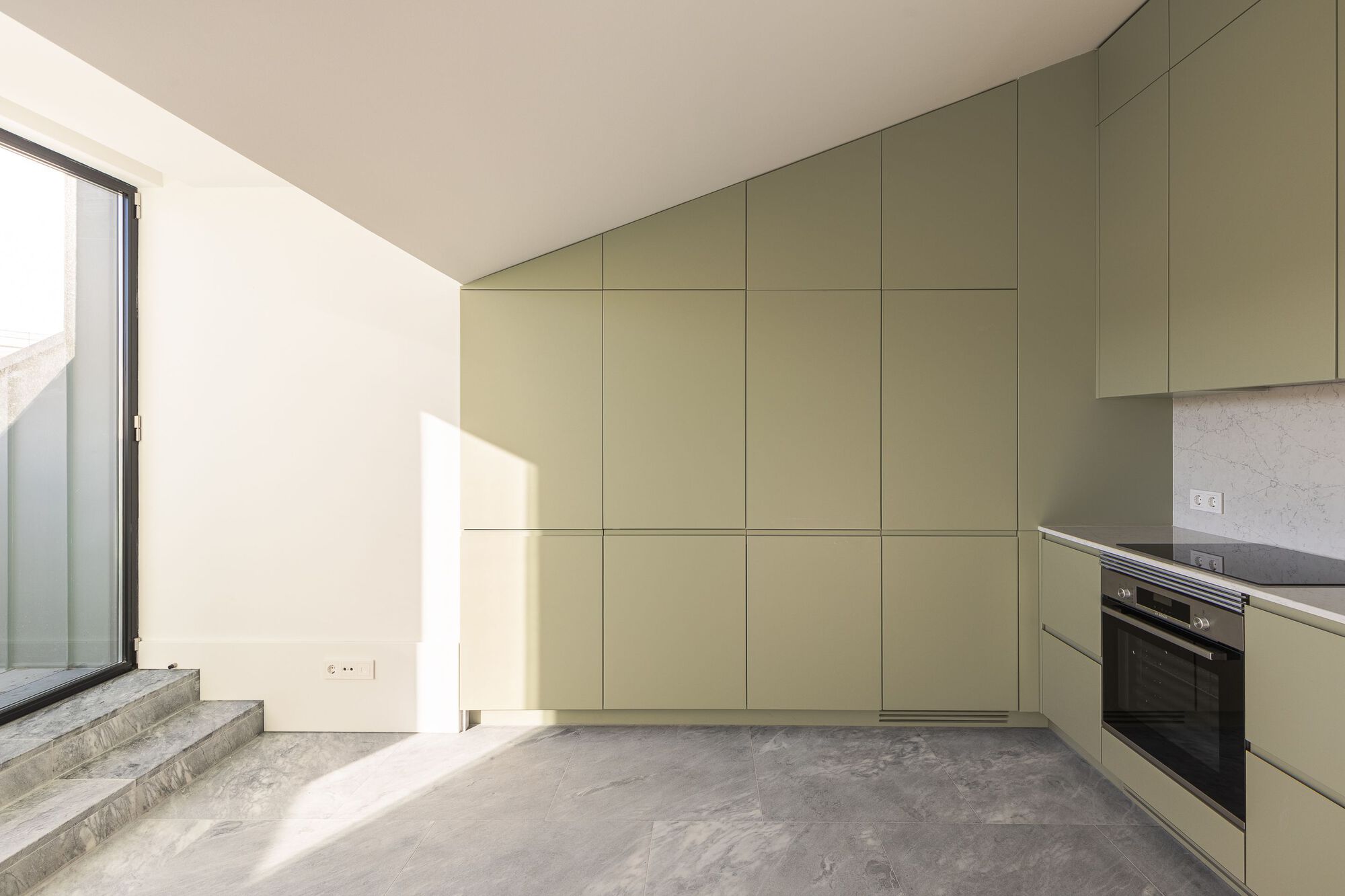 Room with full-height olive-green cabinetry and concrete floor beside granite stairs to an outdoor terrace