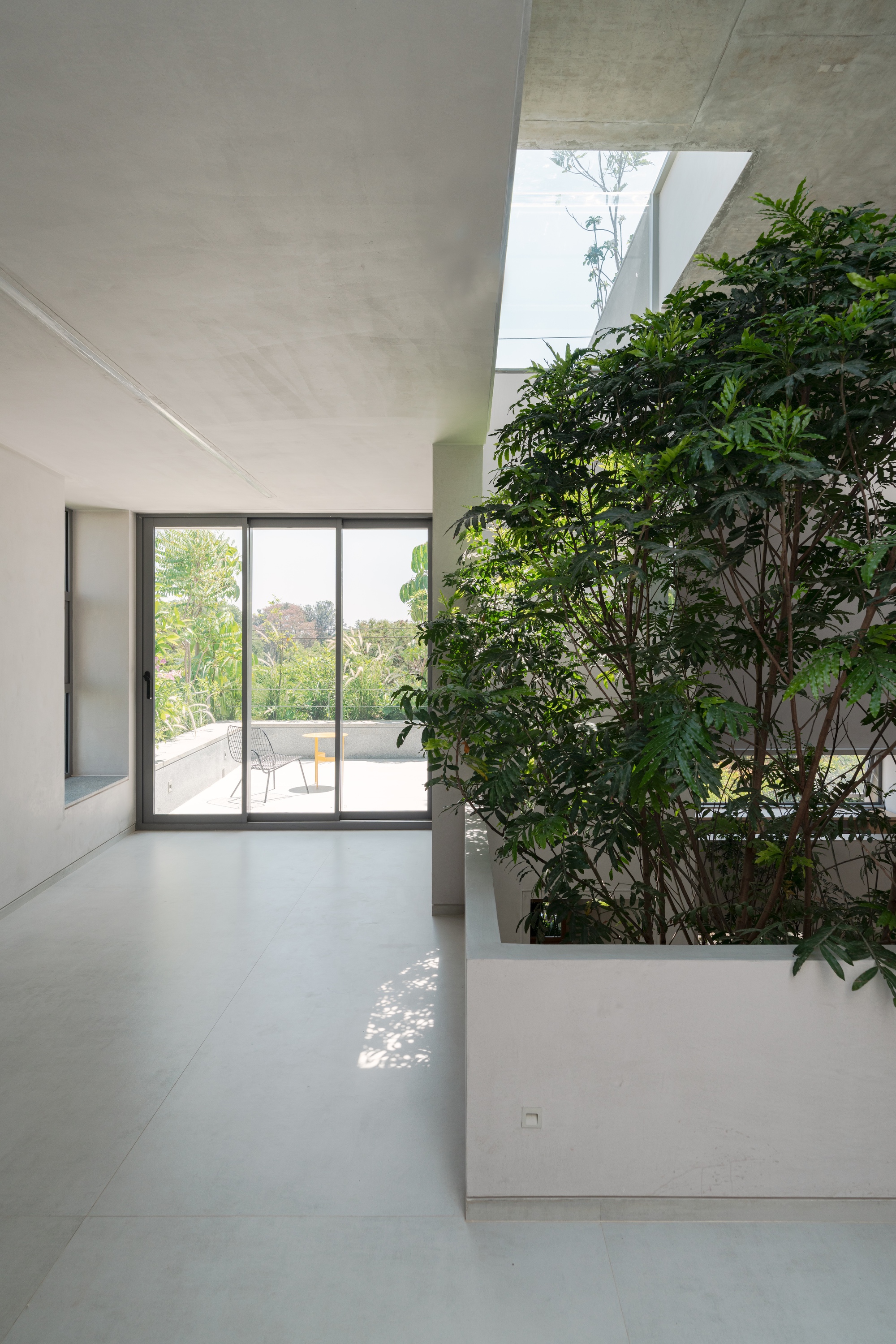 Interior space with raised planter bed beside glazed doors opening to exterior terrace under skylight