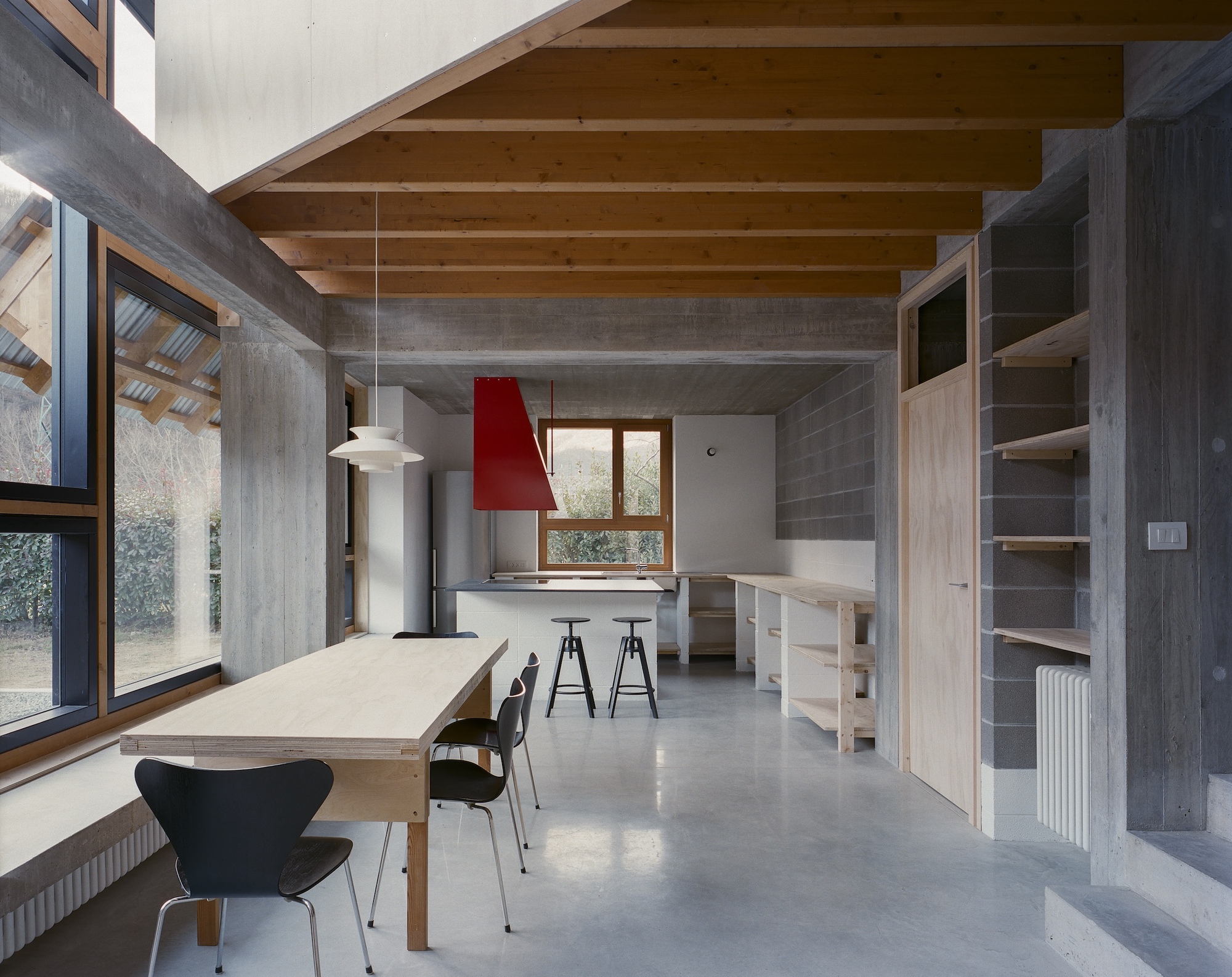 Open-plan kitchen and dining area with exposed timber joists and concrete beams under daylight