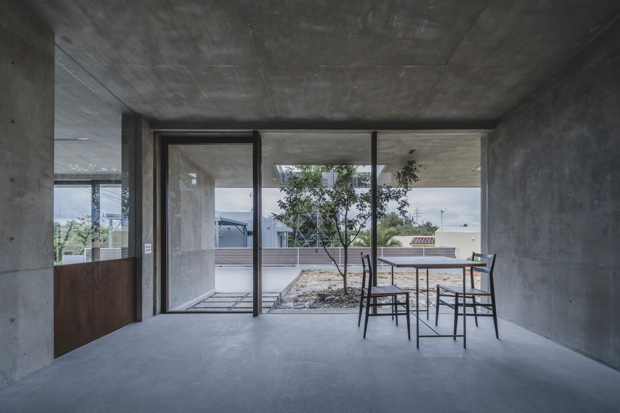 Living space with sliding glass doors framing view of interior courtyard with planted tree