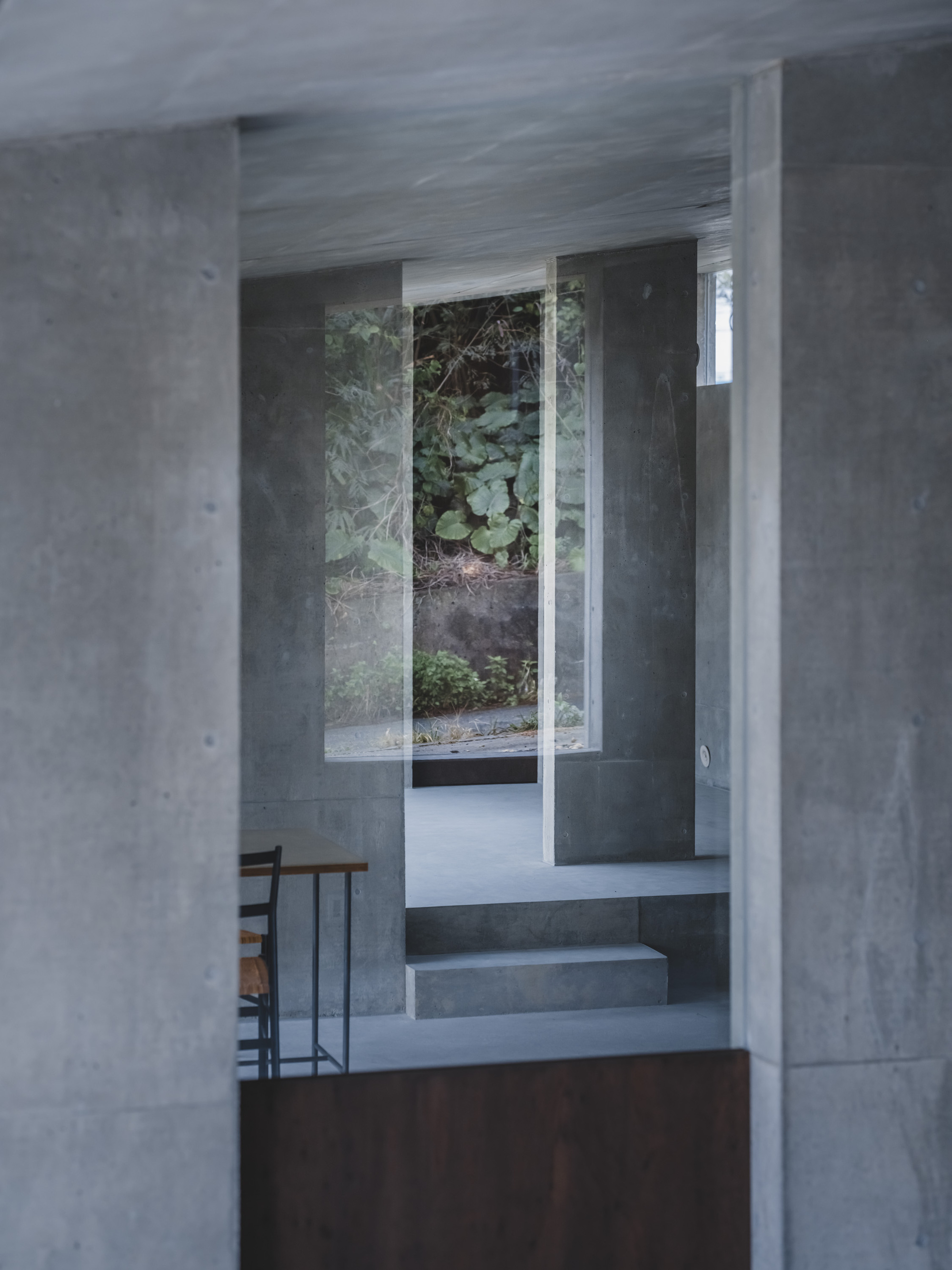 Concrete staircase leading up to glazed opening with vegetation visible beyond the threshold