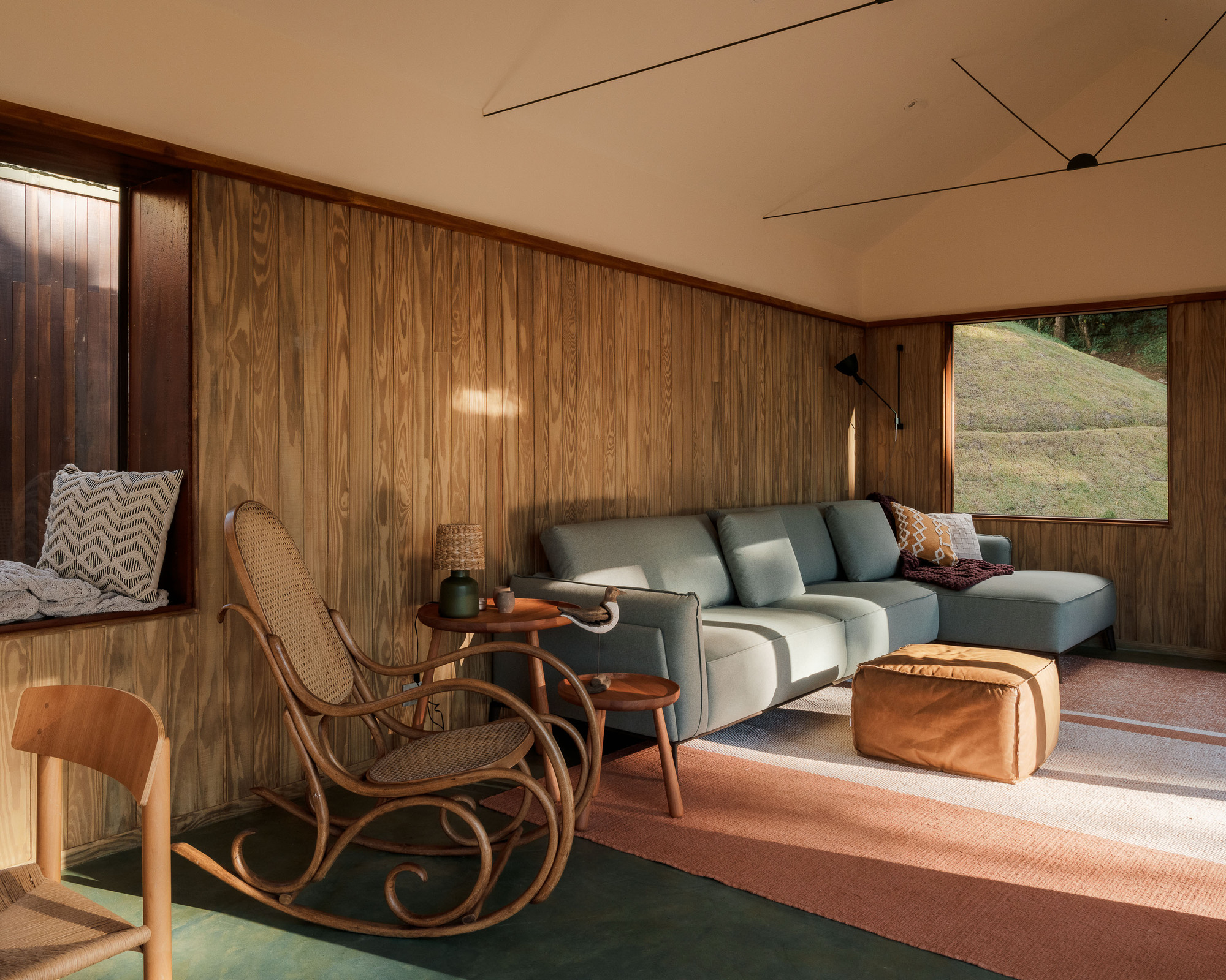 Sitting area with vertical timber walls, plywood ceiling, and afternoon light through horizontal window