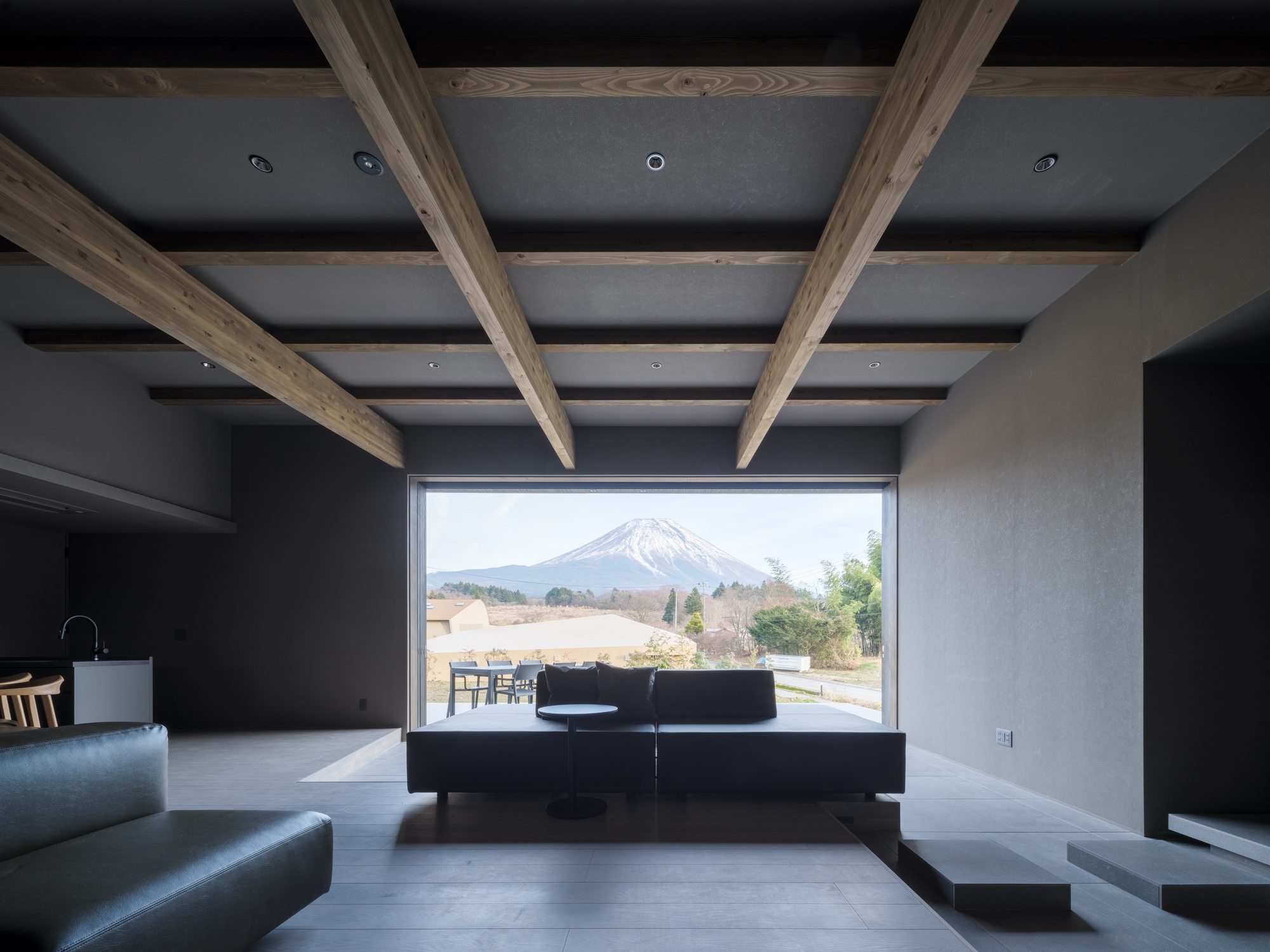 Living room with exposed timber beams and horizontal window overlooking mountain landscape