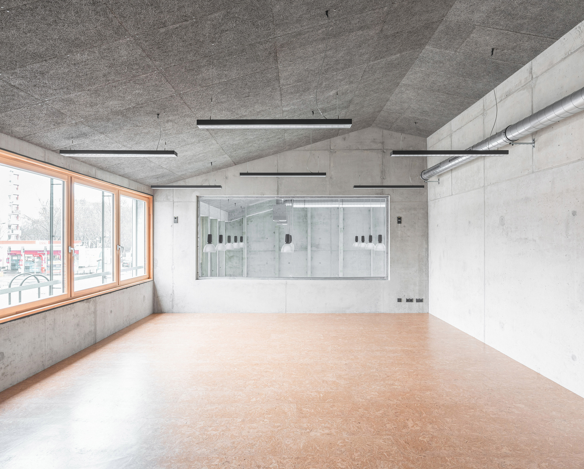 Corner room with linoleum flooring and a glazed interior partition overlooking an adjacent space