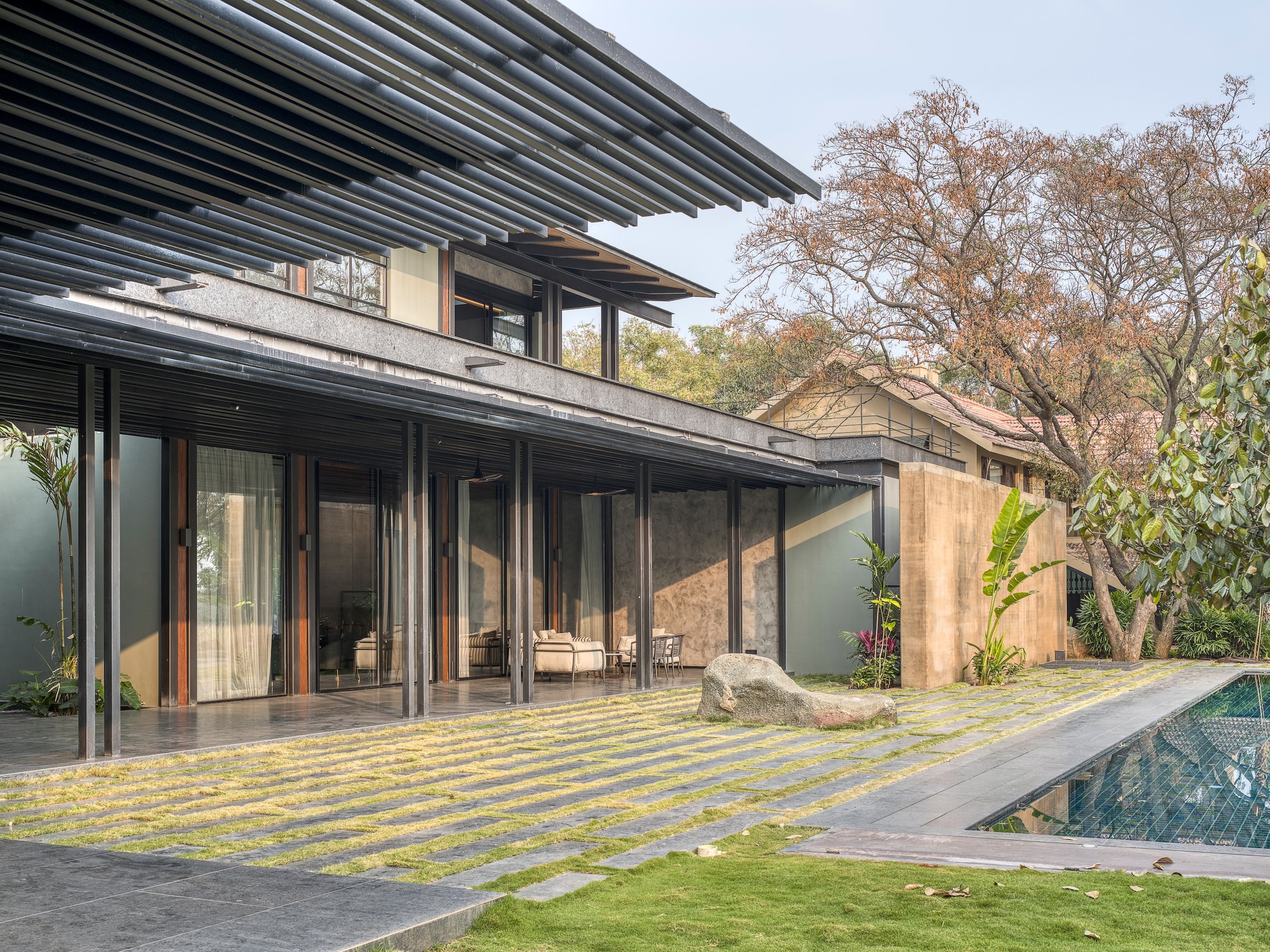 Poolside terrace with striped yellow paving and glass sliding doors opening to the living spaces