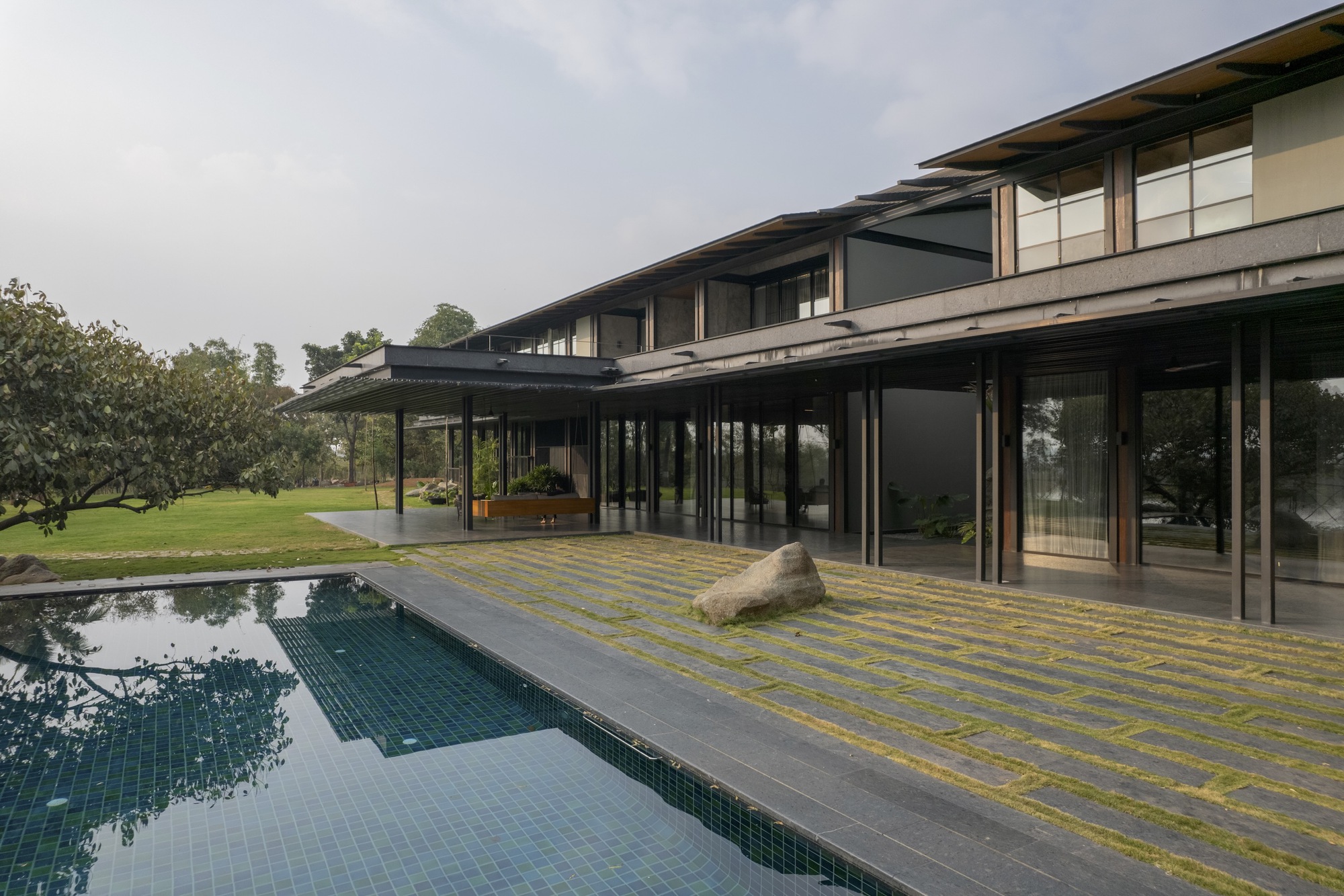 Covered outdoor terrace with steel columns extending along the pool deck and tiled mosaic paving