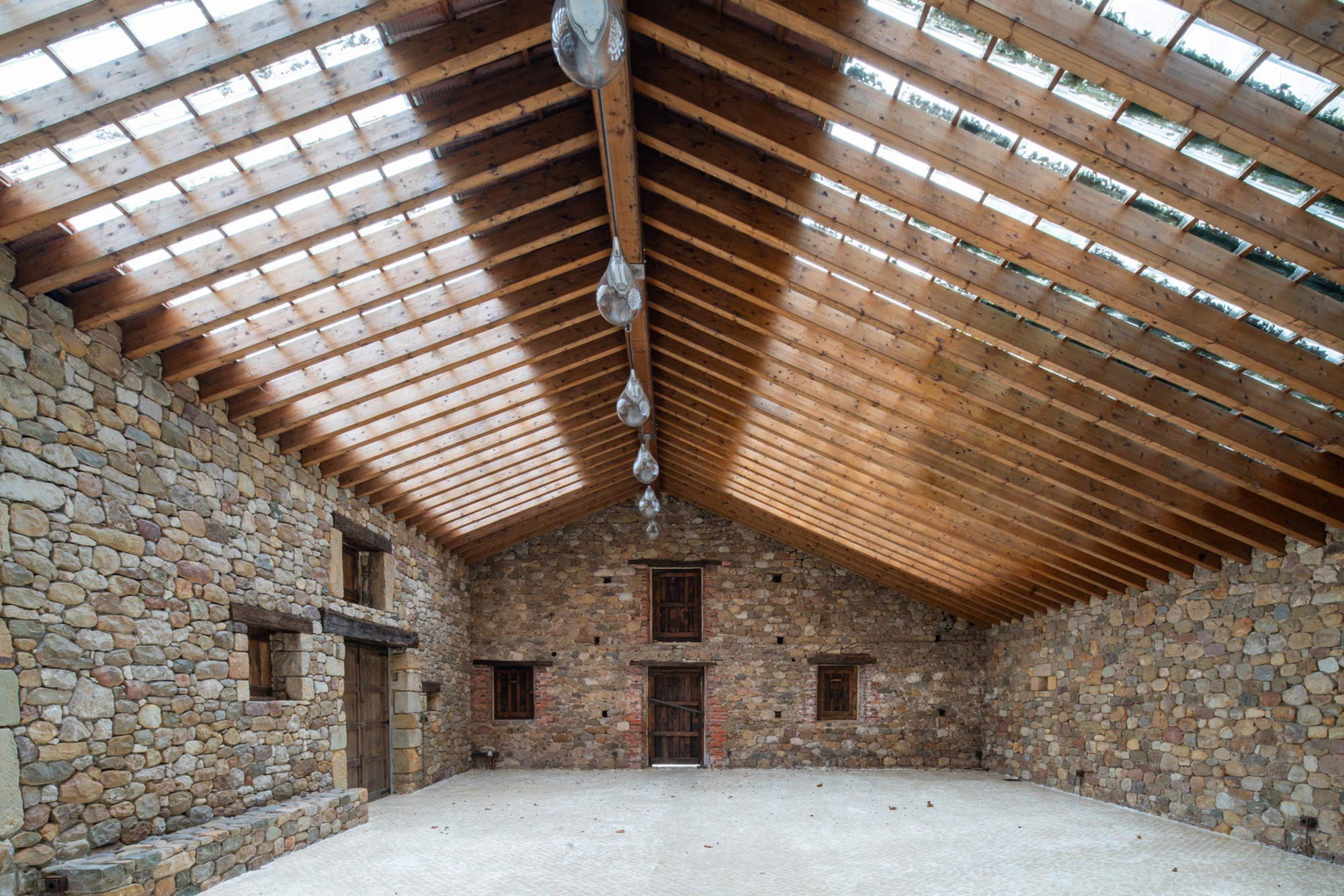 Interior view of the exposed timber rafter ceiling meeting stone walls with window openings