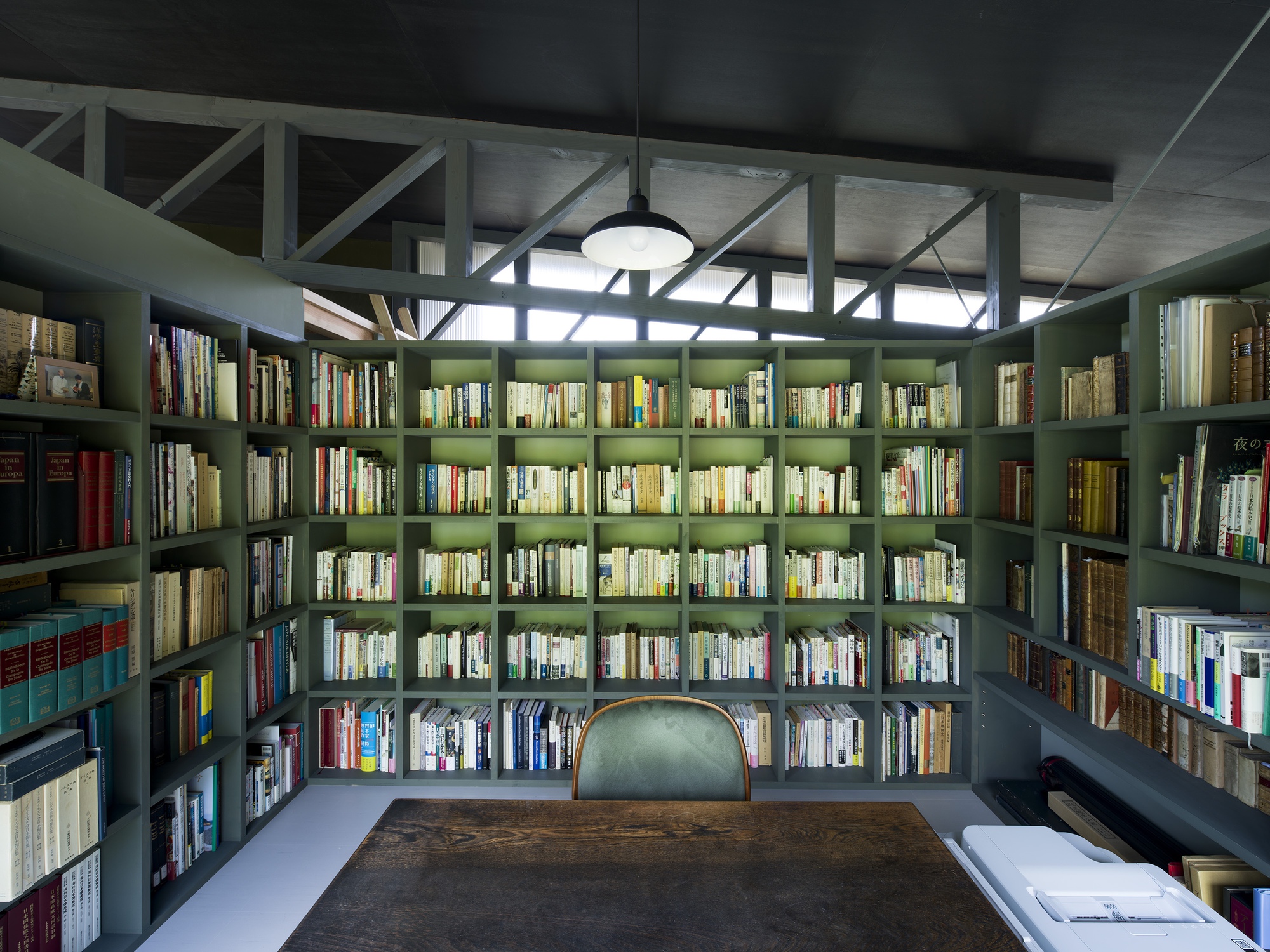 Library with floor-to-ceiling bookshelves and diagonal braced glazing above under concrete ceiling