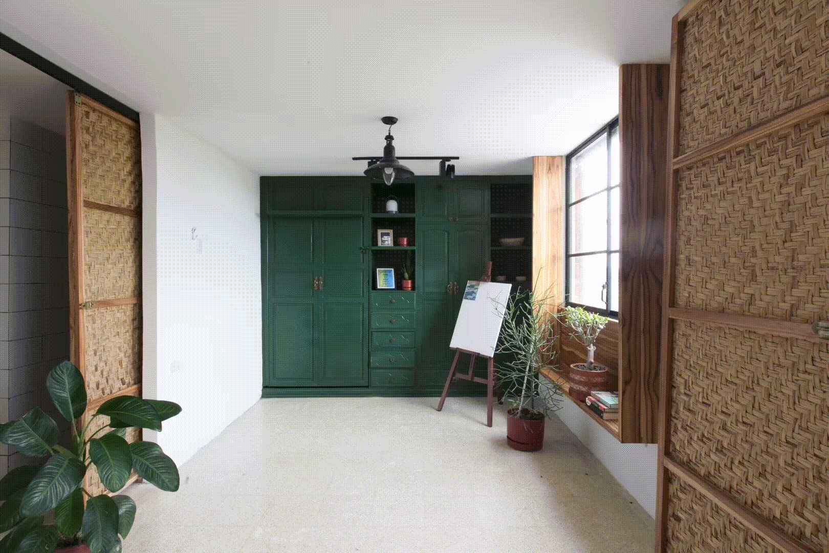 Interior hallway with dark green cabinetry, woven rattan sliding panels, and potted plants near the window
