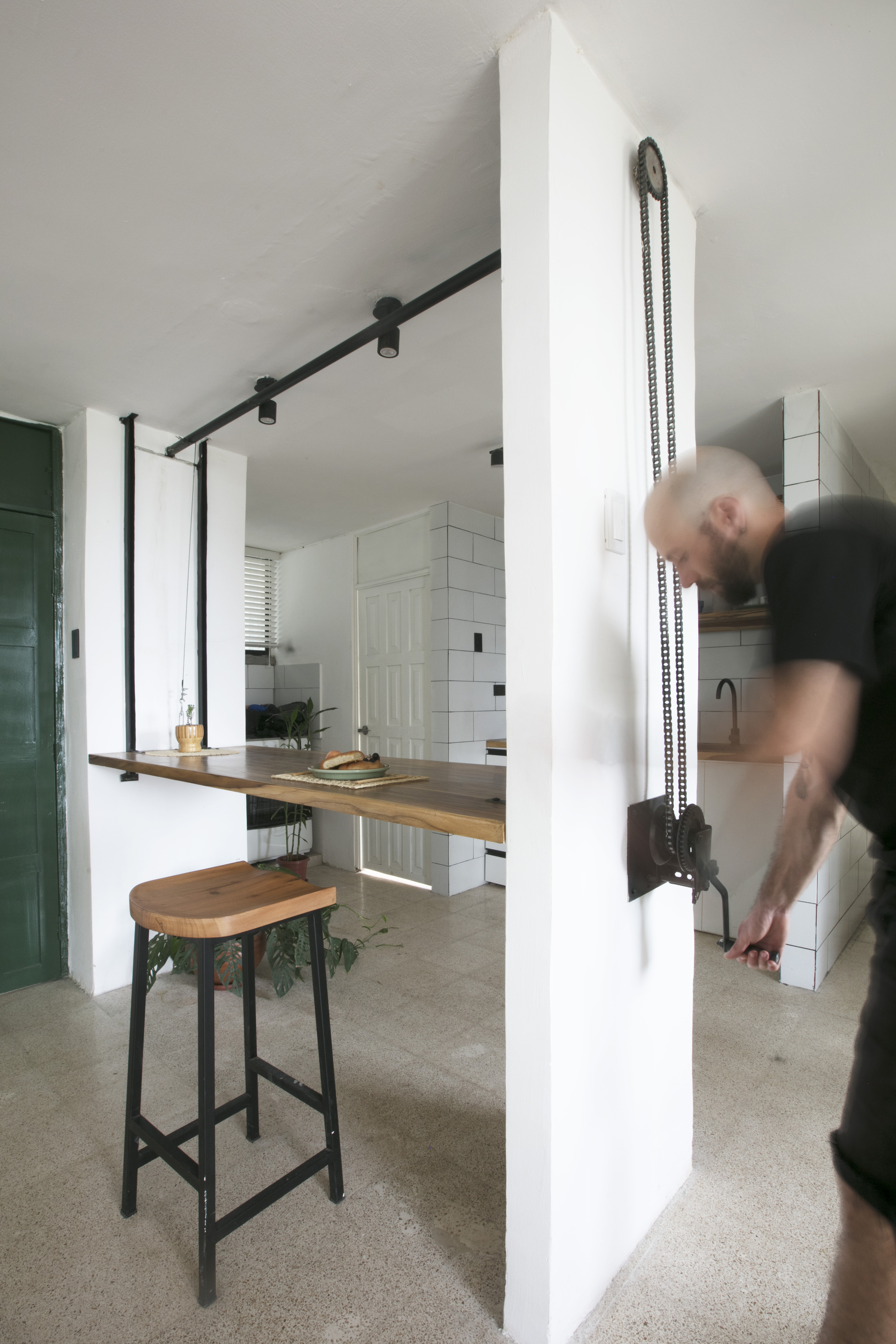 Kitchen passthrough with fold-down timber counter and a person in motion adjusting the chain mechanism
