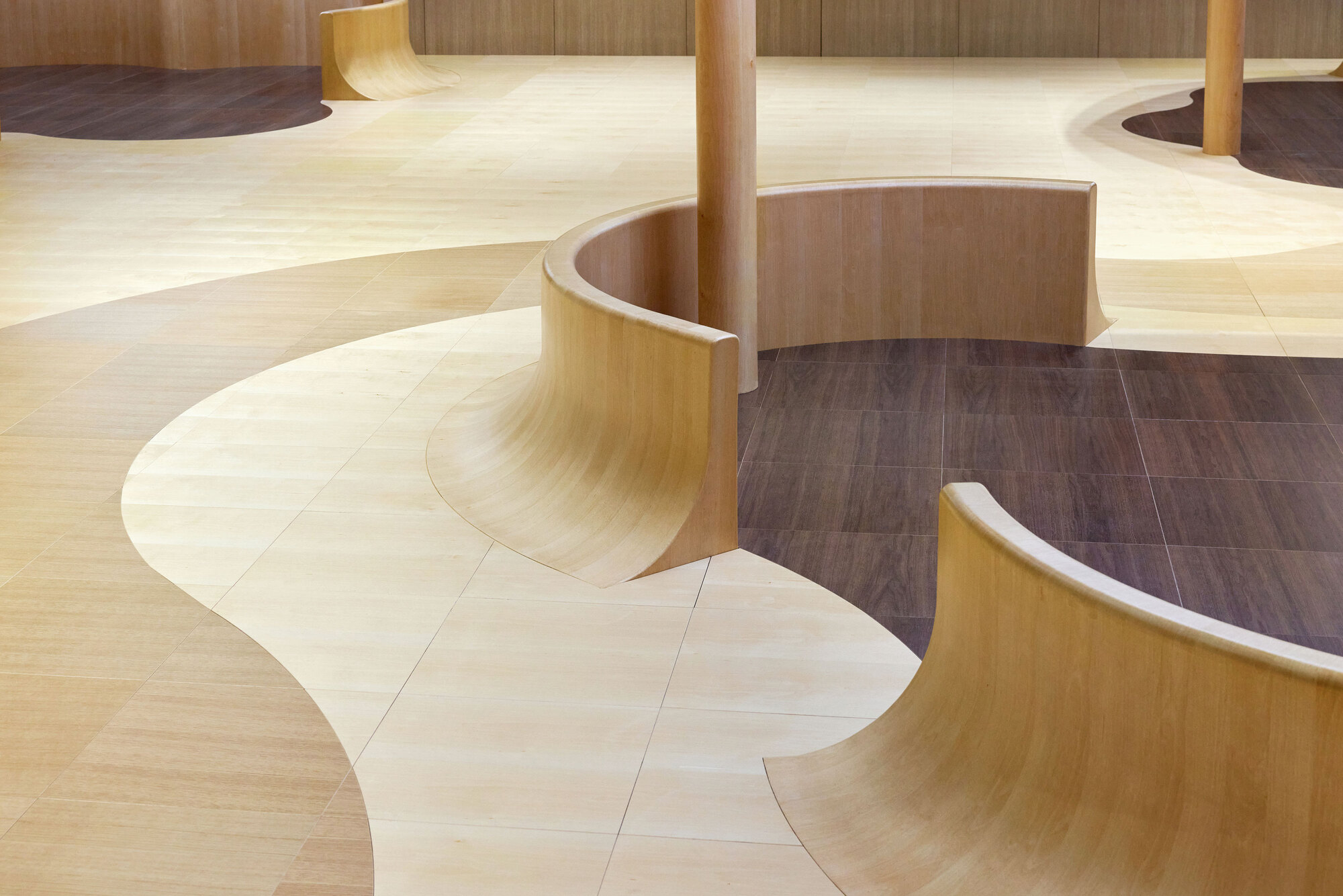 Detail of the flowing plywood floor transitions between light and dark timber surfaces around a column base