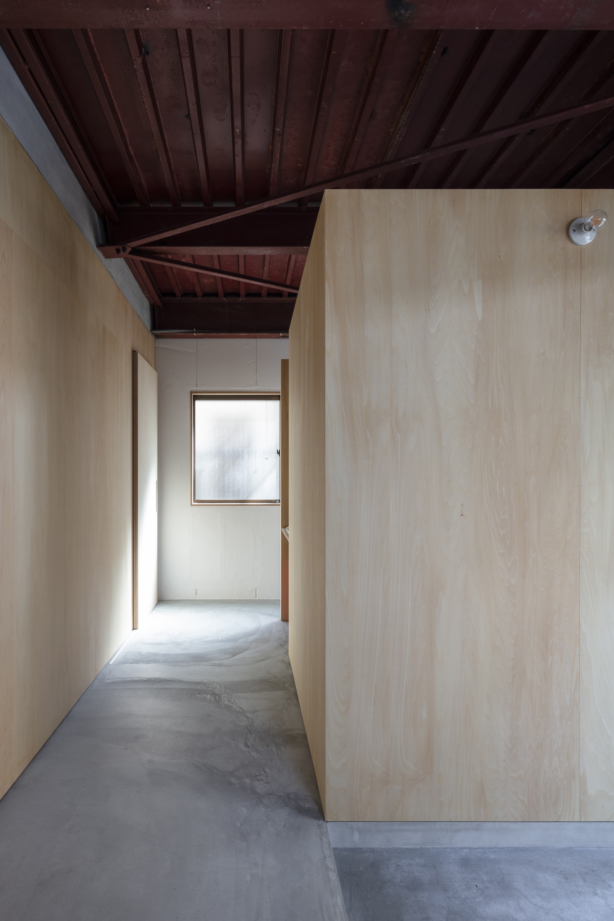 Hallway with exposed reddish-brown timber roof beams and polished concrete floor