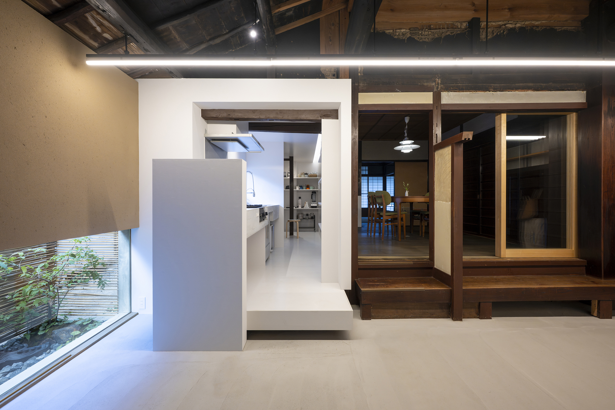 View through doorway to kitchen with exposed timber framing and raised dining platform at dusk