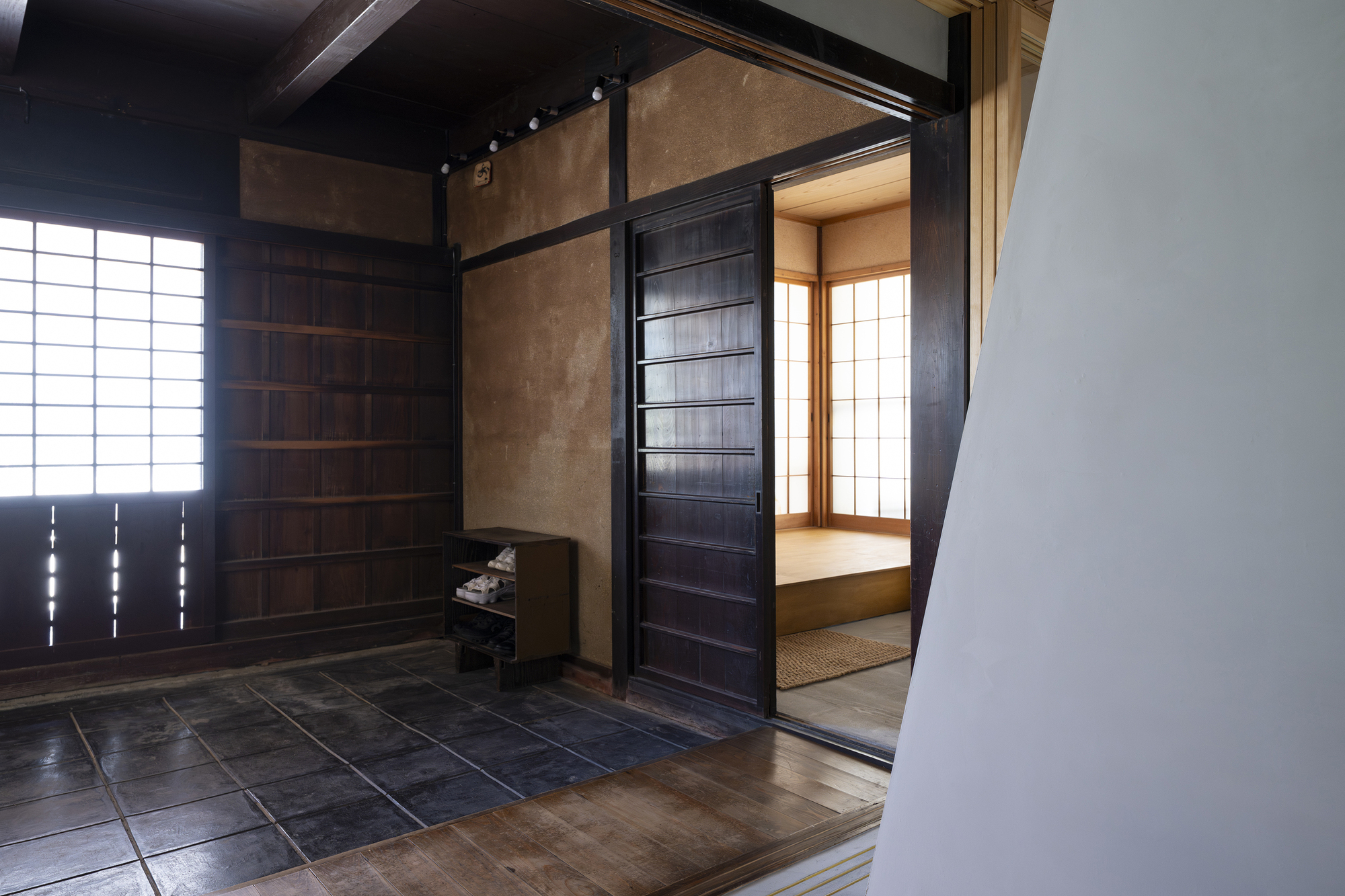 Entrance vestibule with dark stone tile floor and sliding timber door opening to tatami room with paper screens