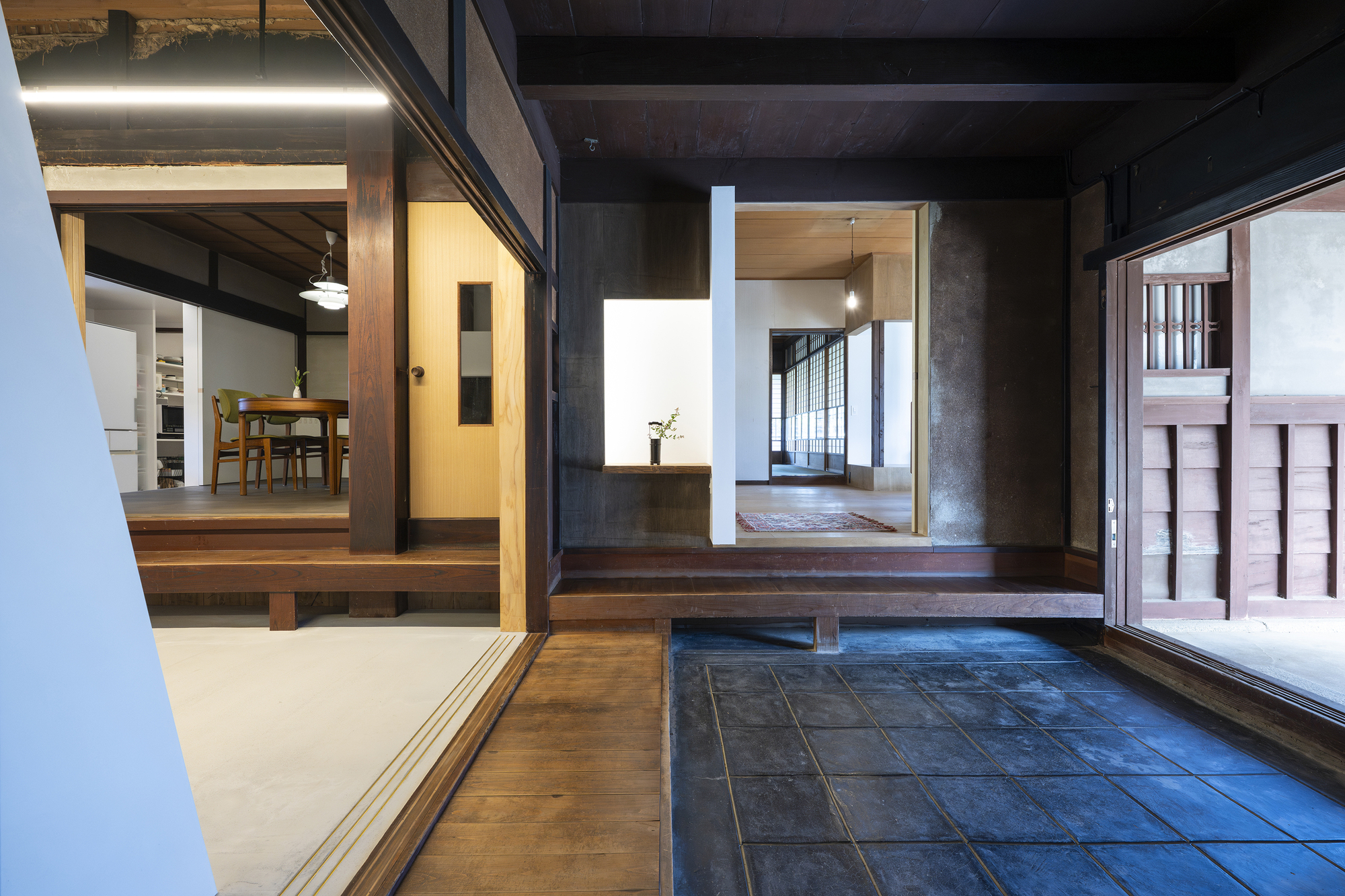 Tiled entrance vestibule with dark timber framing opening to illuminated interior rooms beyond