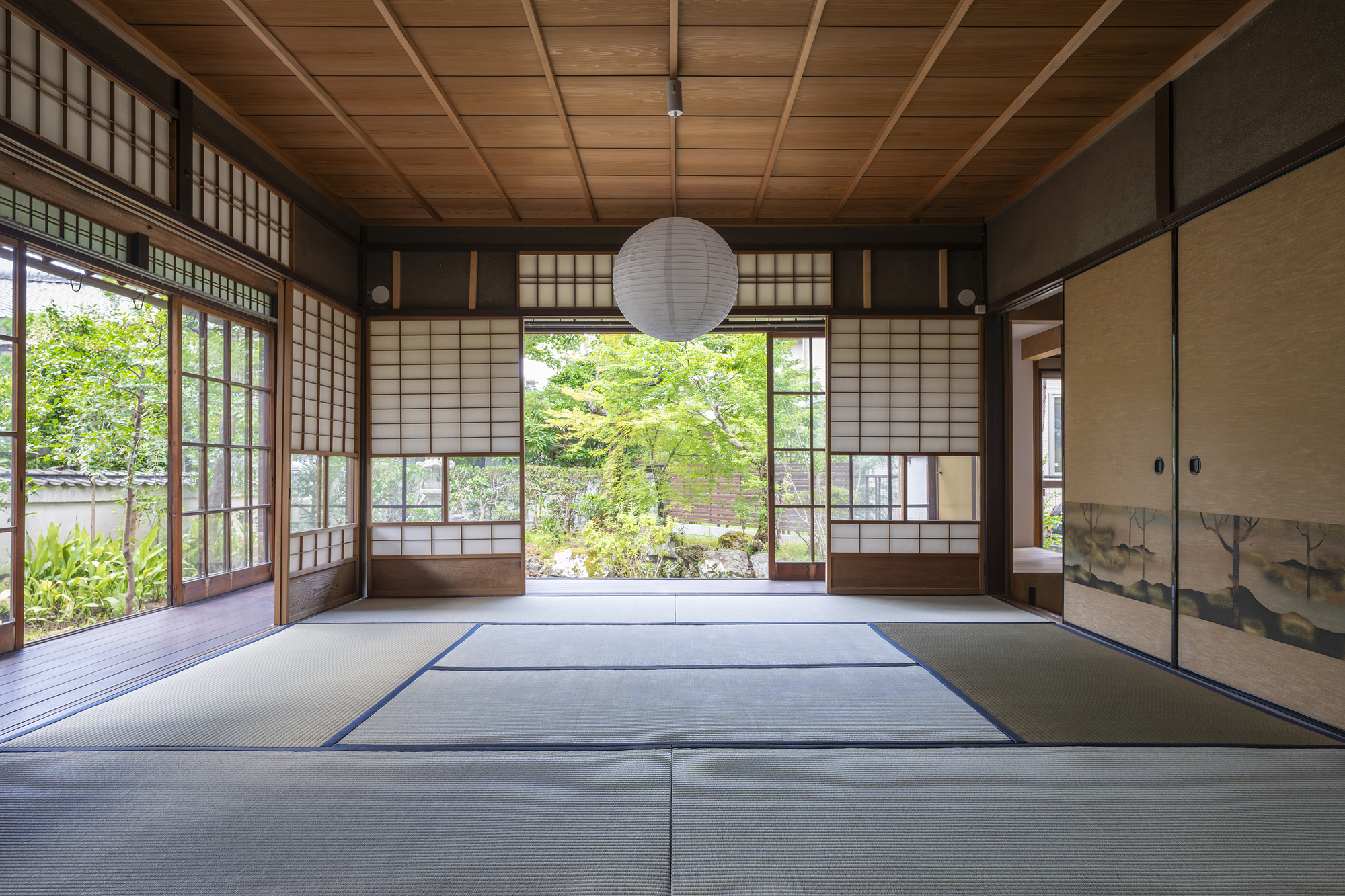 Tatami mat room with coffered timber ceiling and sliding shoji screens facing a garden courtyard