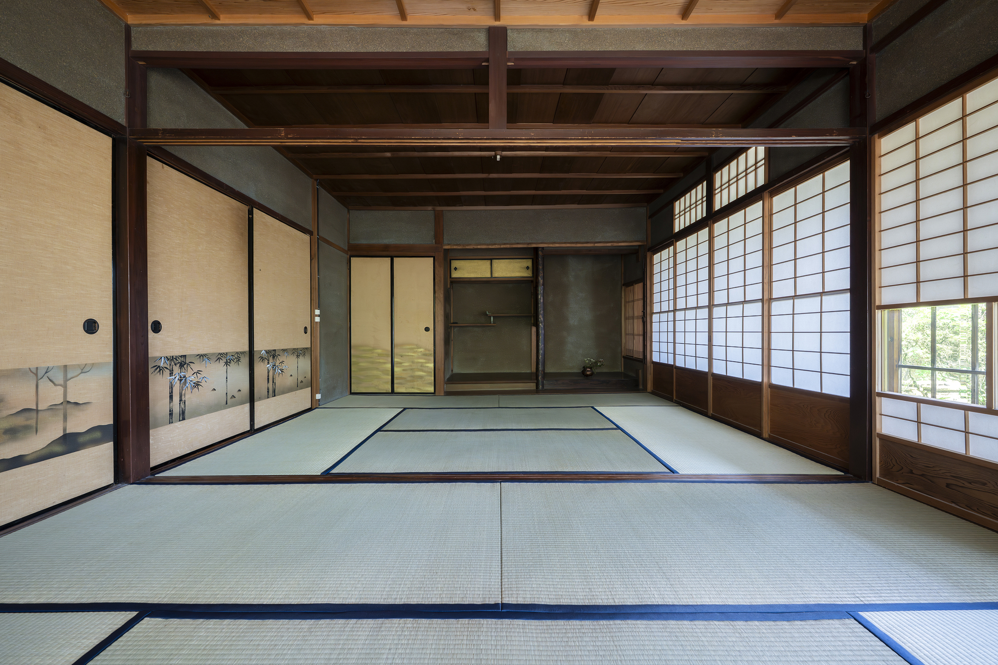Tatami mat room with painted sliding doors and shoji screens framing adjacent interior spaces