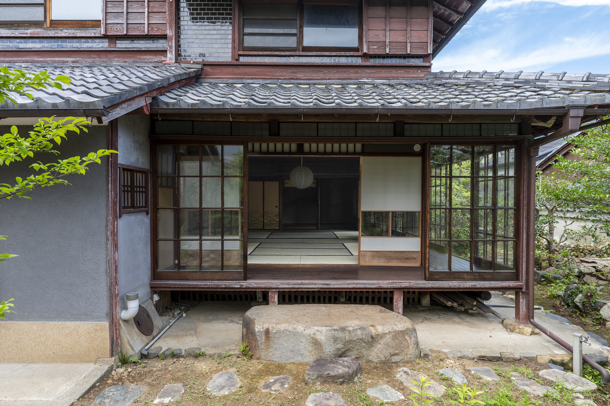 Exterior view of sliding glass doors opening onto raised timber veranda with tiled roof above