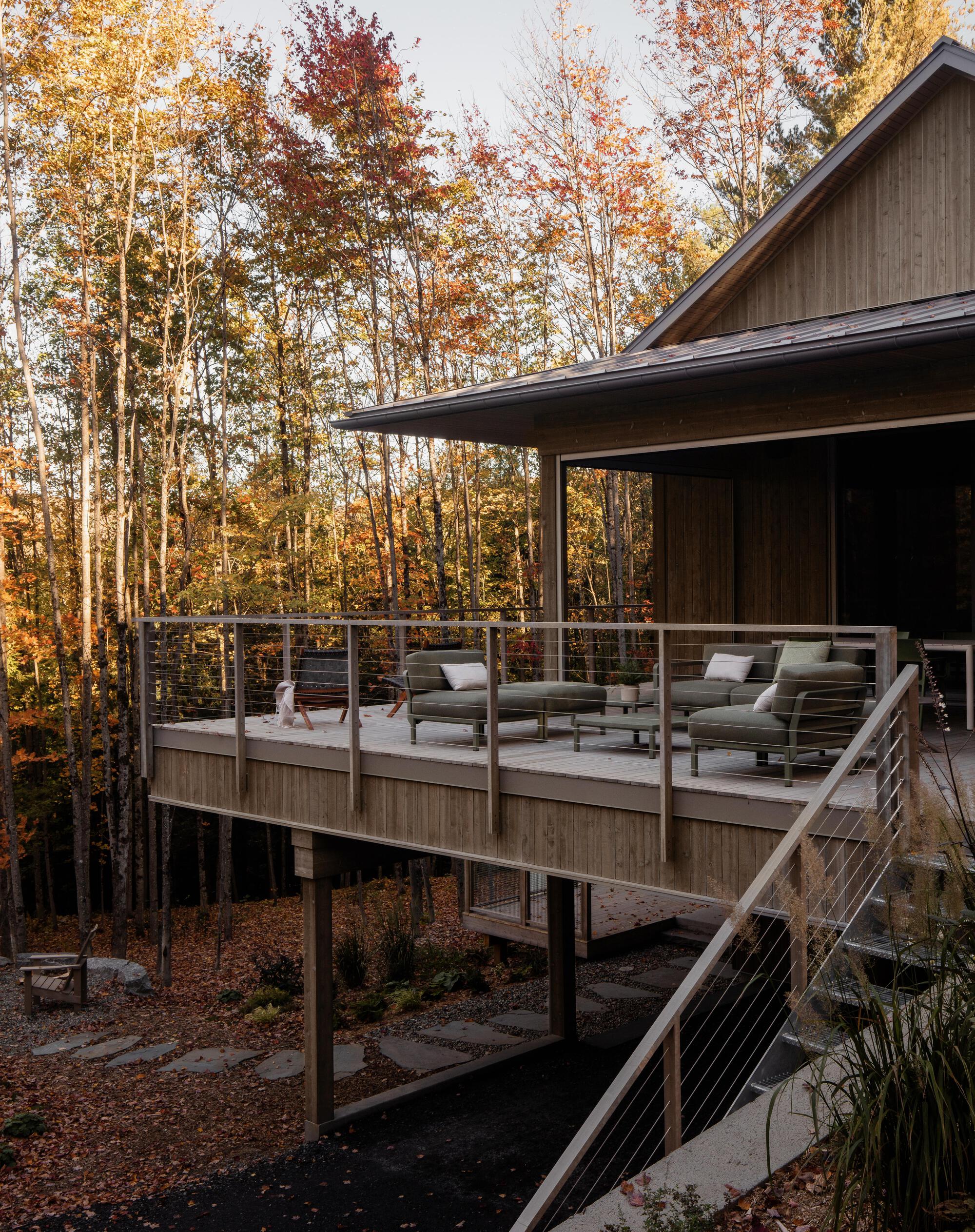 Elevated deck with cable railing and outdoor seating among autumn trees