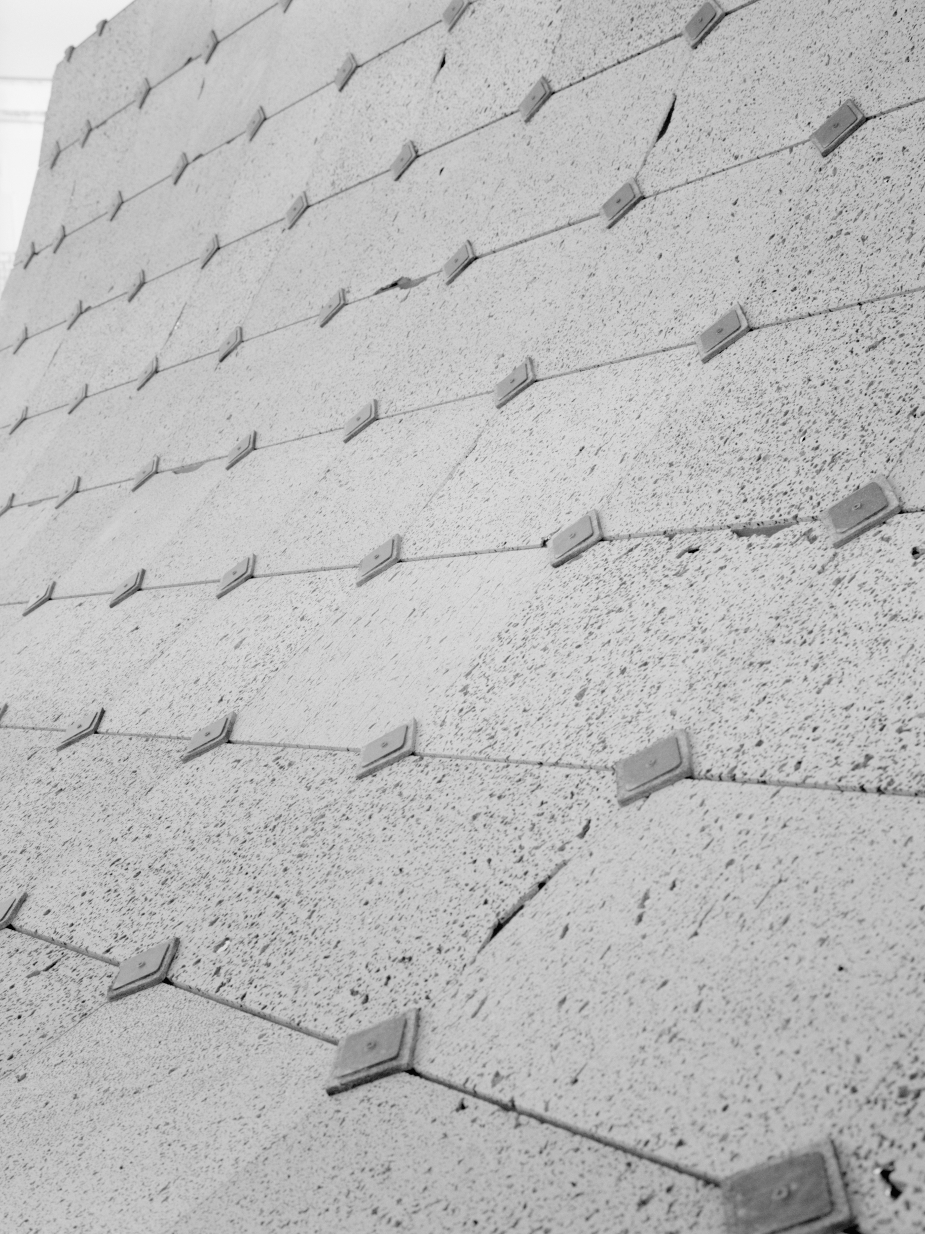 Close-up of textured concrete surface with protruding diamond-shaped metal anchors in diagonal rows