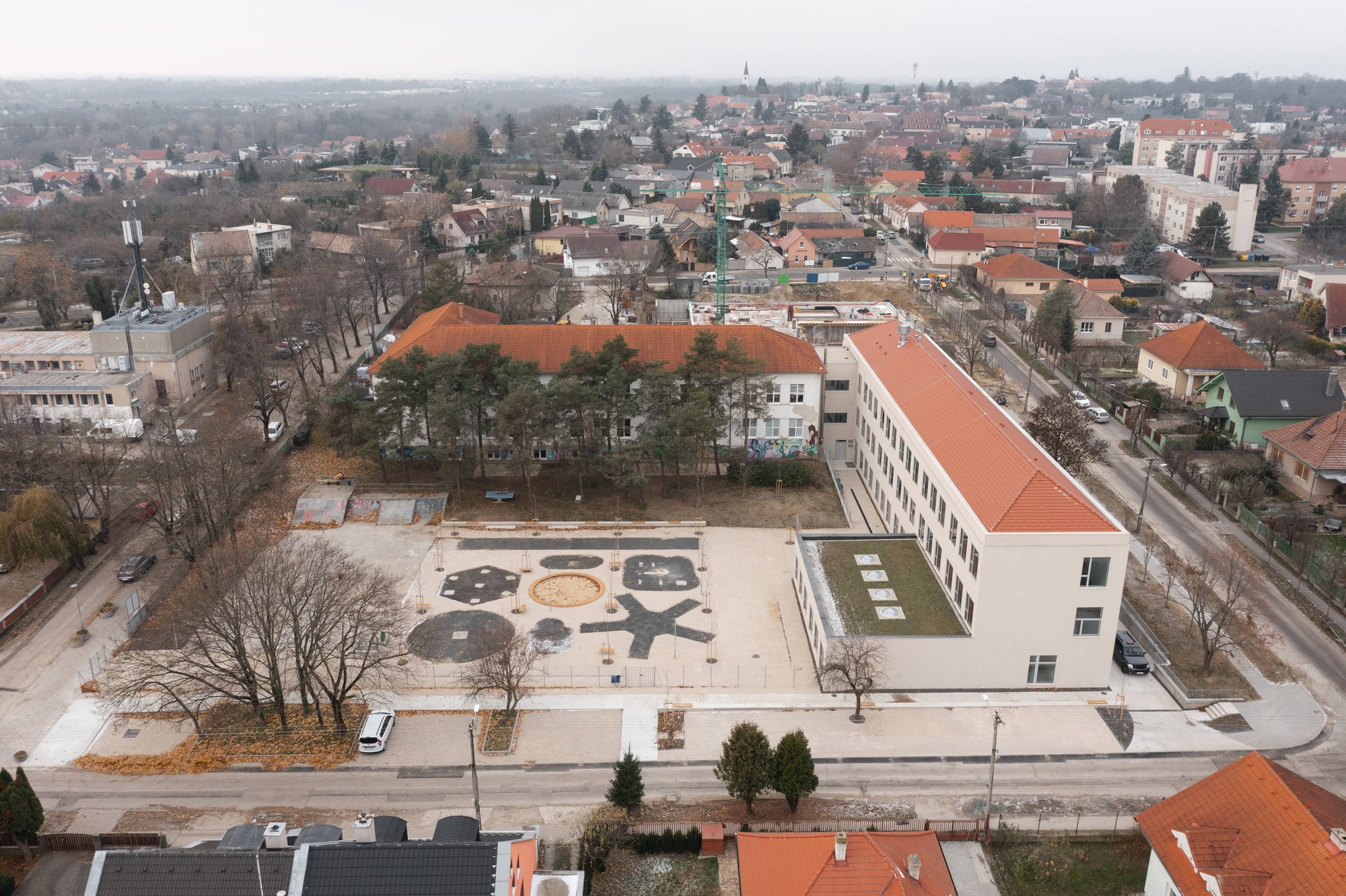 Aerial view of the plaza with geometric paving patterns and a white-roofed building surrounded by bare winter trees