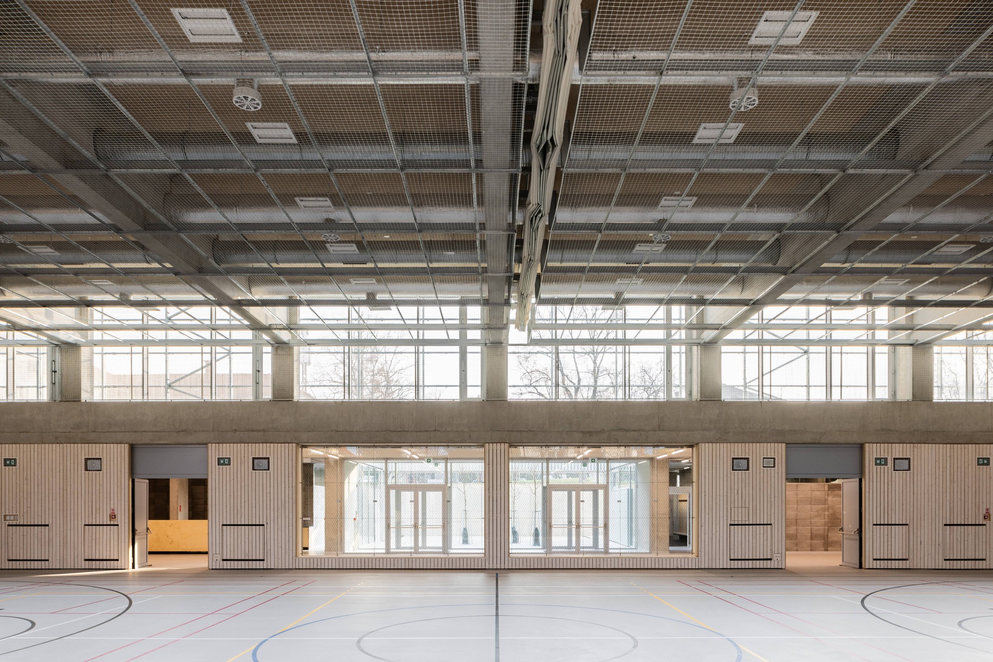 View across the gymnasium showing clerestory windows and timber wall cladding beneath the exposed ceiling structure