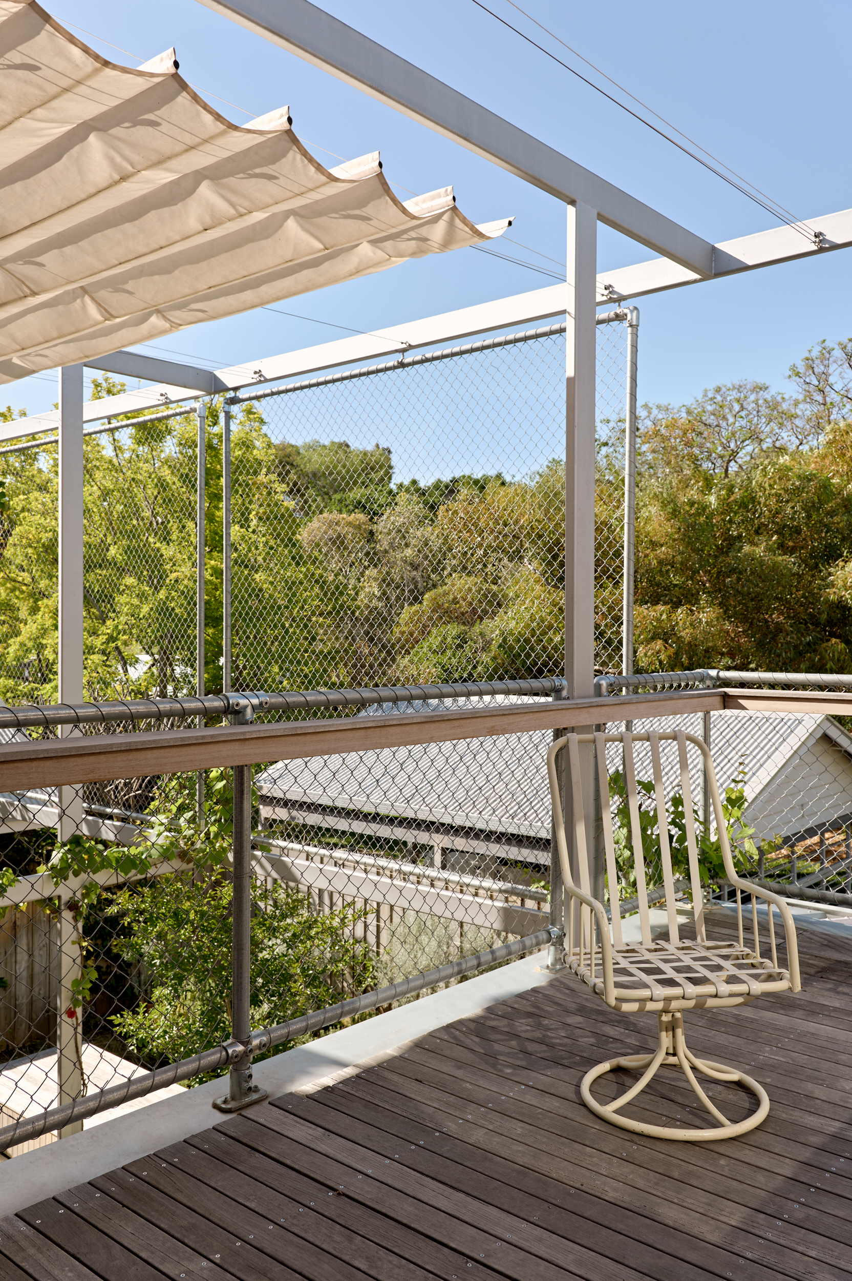 Rooftop deck with chain-link mesh balustrade, retractable canvas shade and single suspended chair