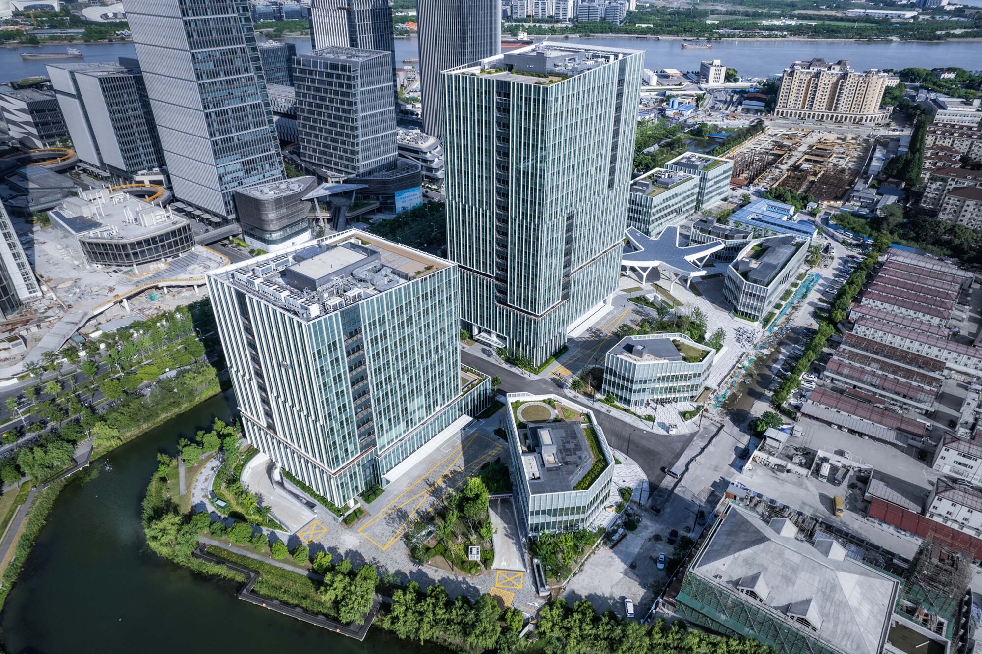 Aerial view of the campus showing glass towers and white canopy structure beside a waterfront canal