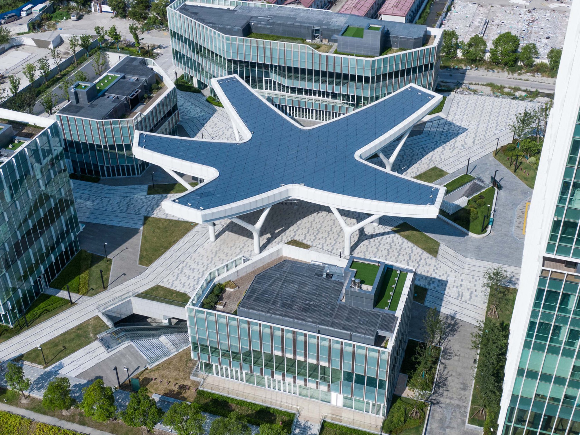 Drone view of the white steel canopy with six radiating arms above a paved plaza