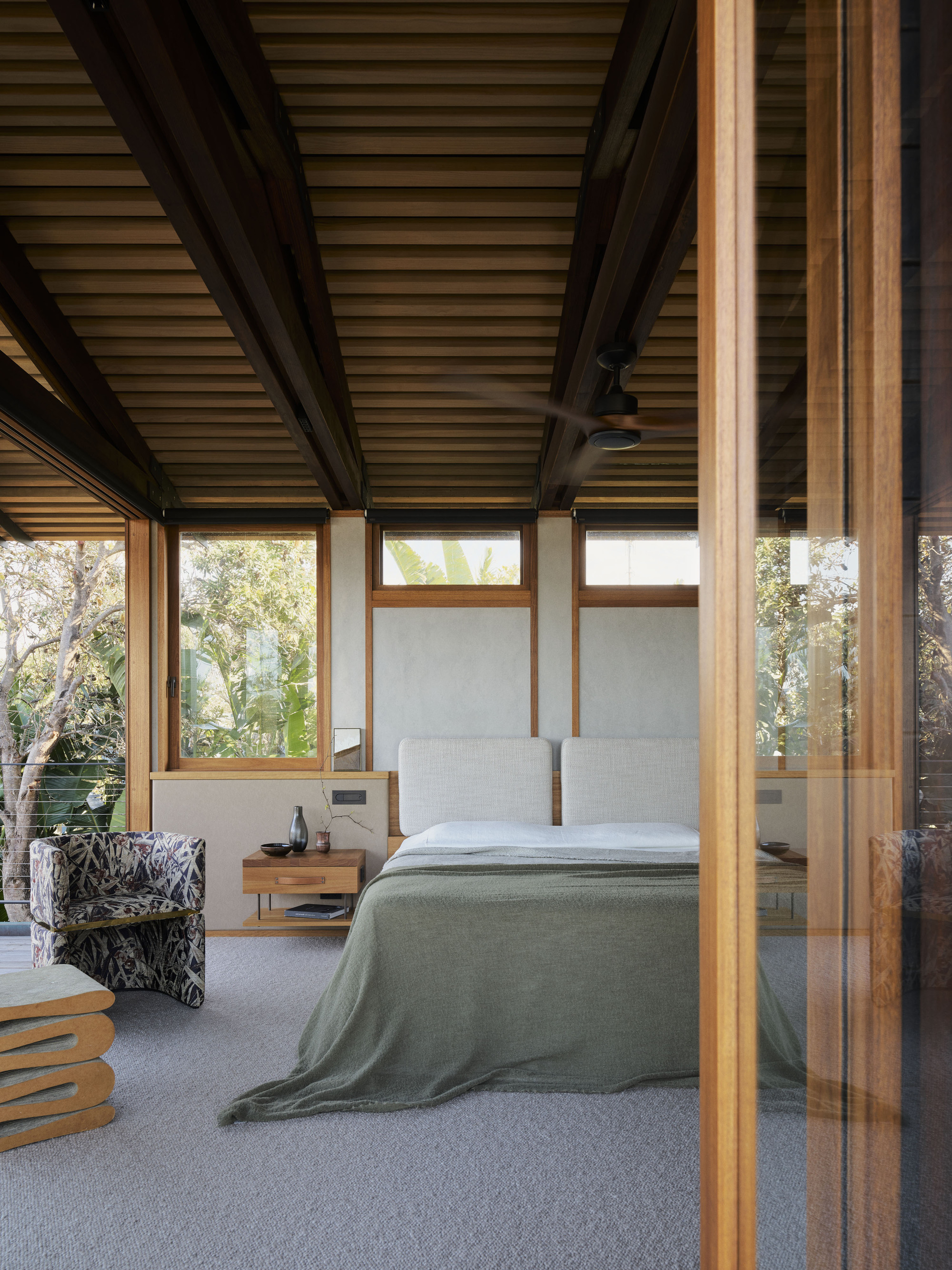Bedroom with dark timber structure and continuous ribbon windows overlooking treetops