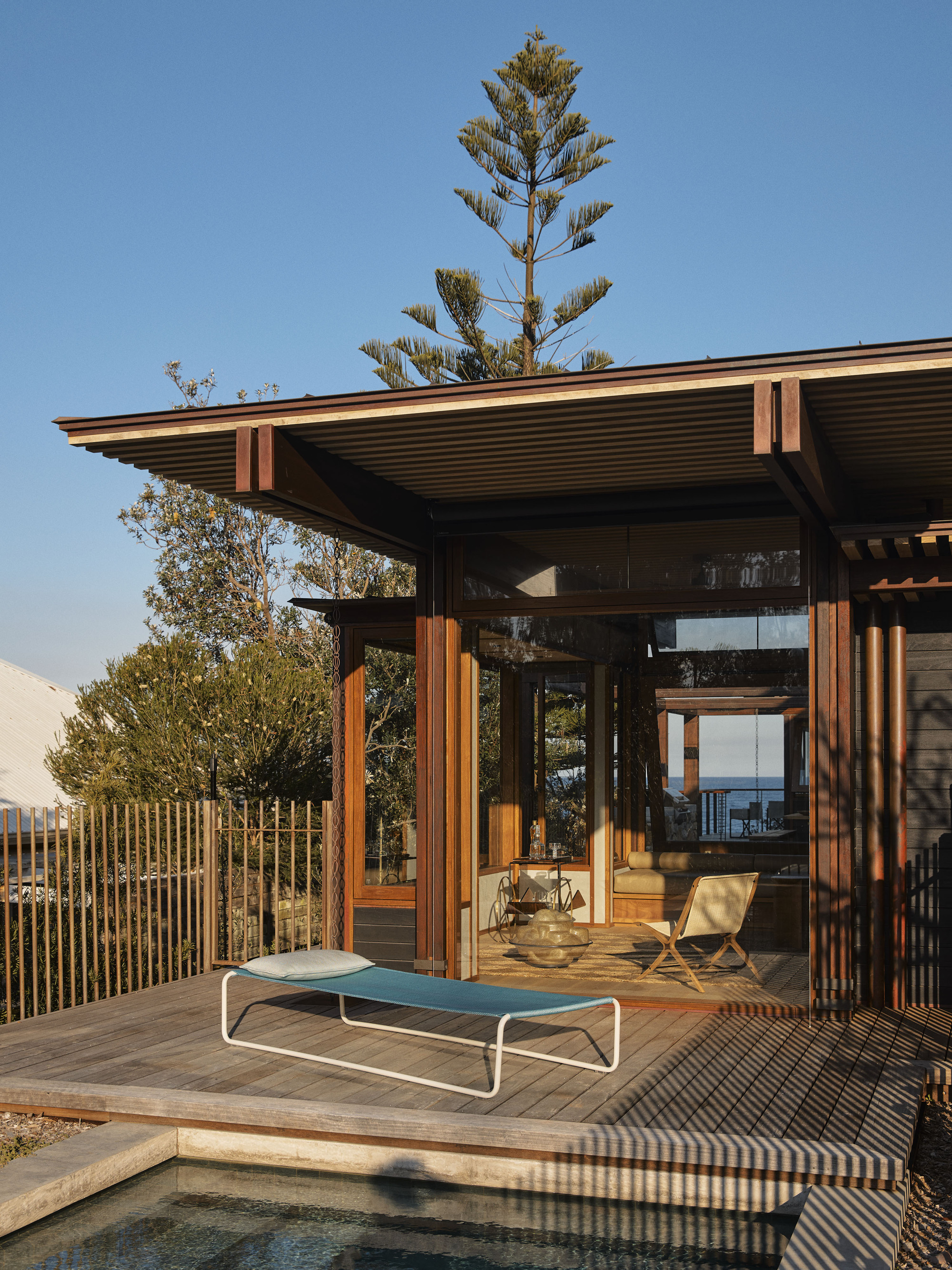 Poolside deck with timber louvered screens and wide eaves in late afternoon sunlight