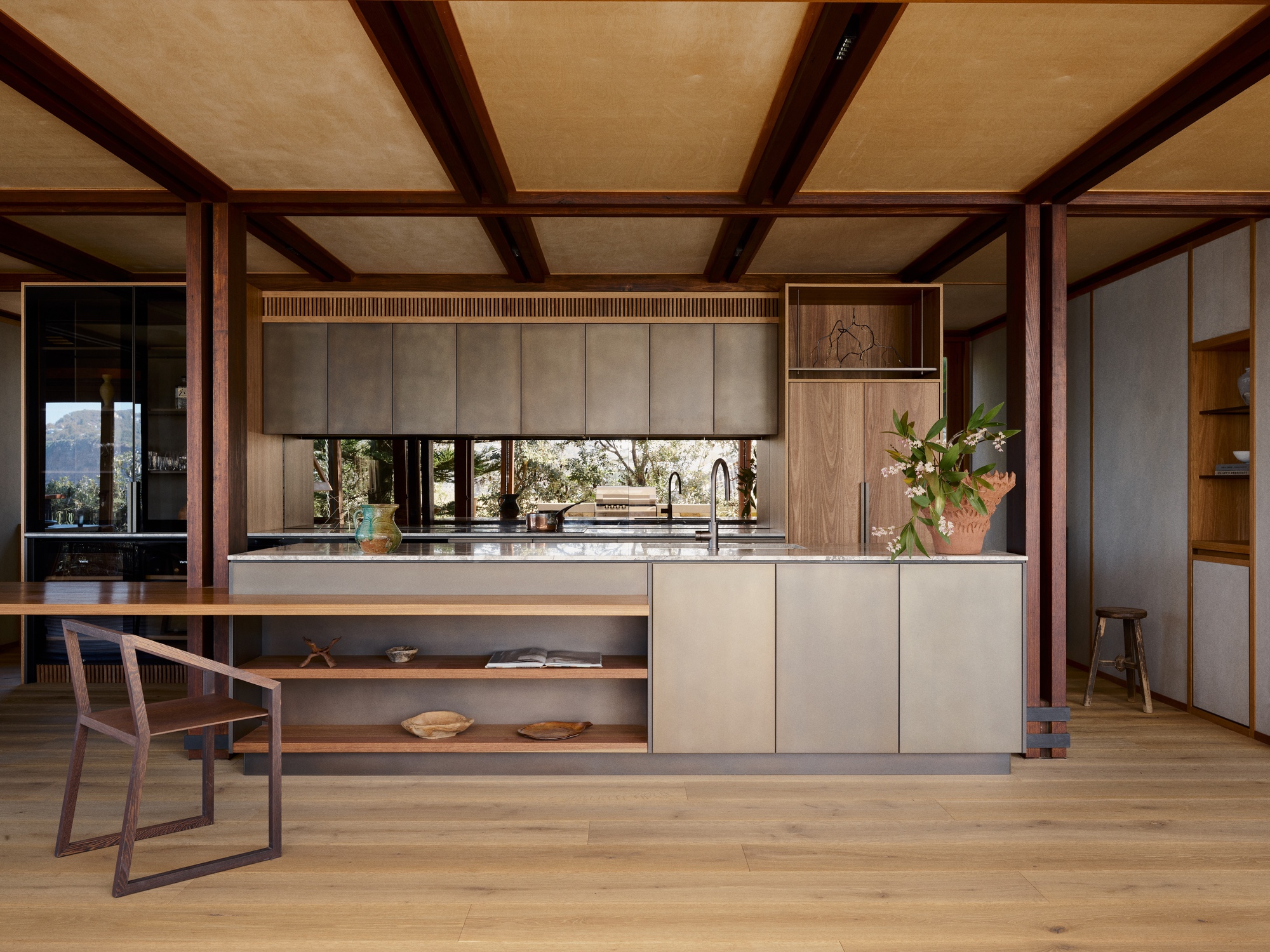 Kitchen island with pale cabinetry and timber frame structure beneath flat ceiling panels
