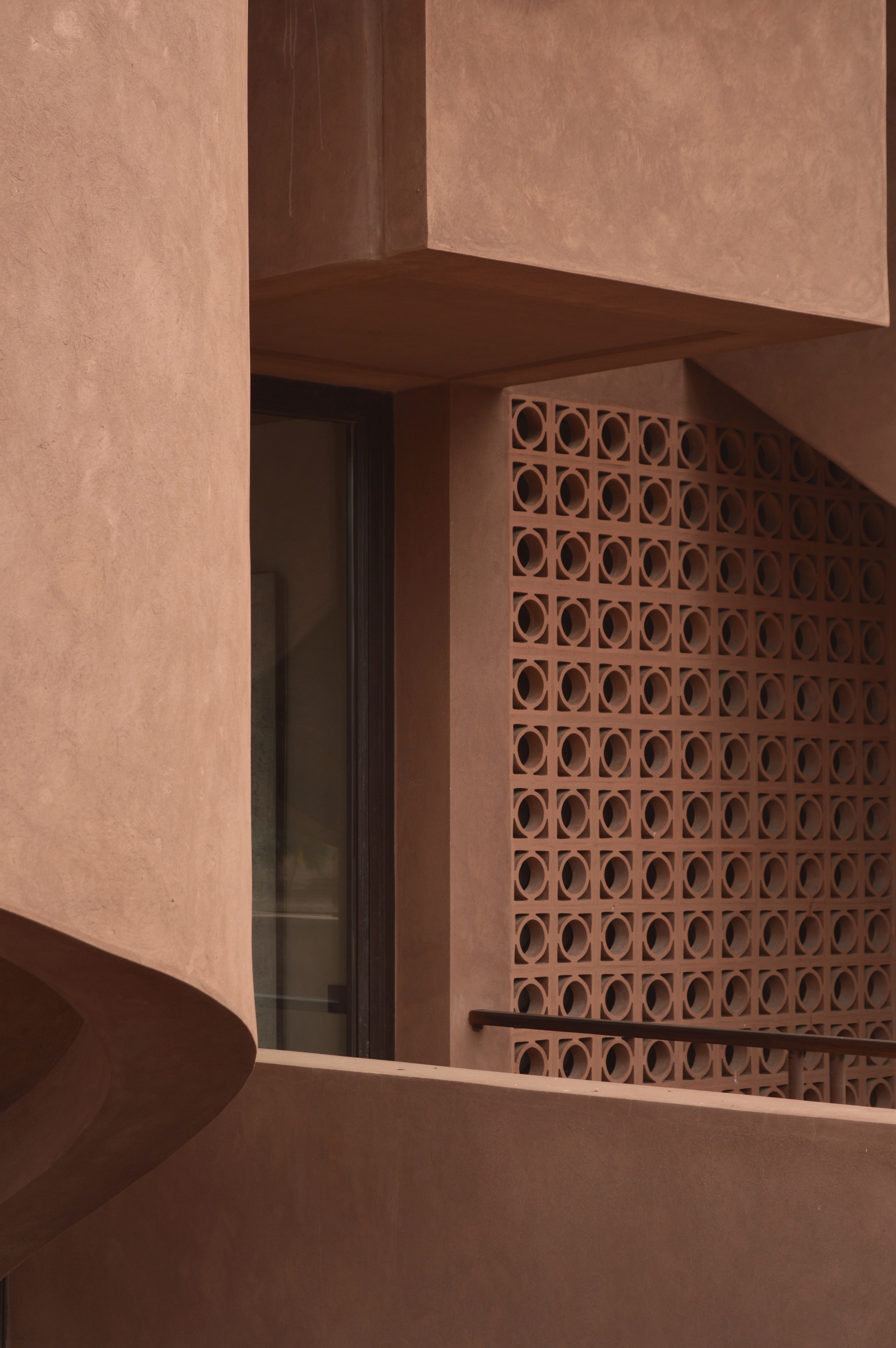 Terracotta breeze block screen beside a dark timber doorway beneath a plastered beam