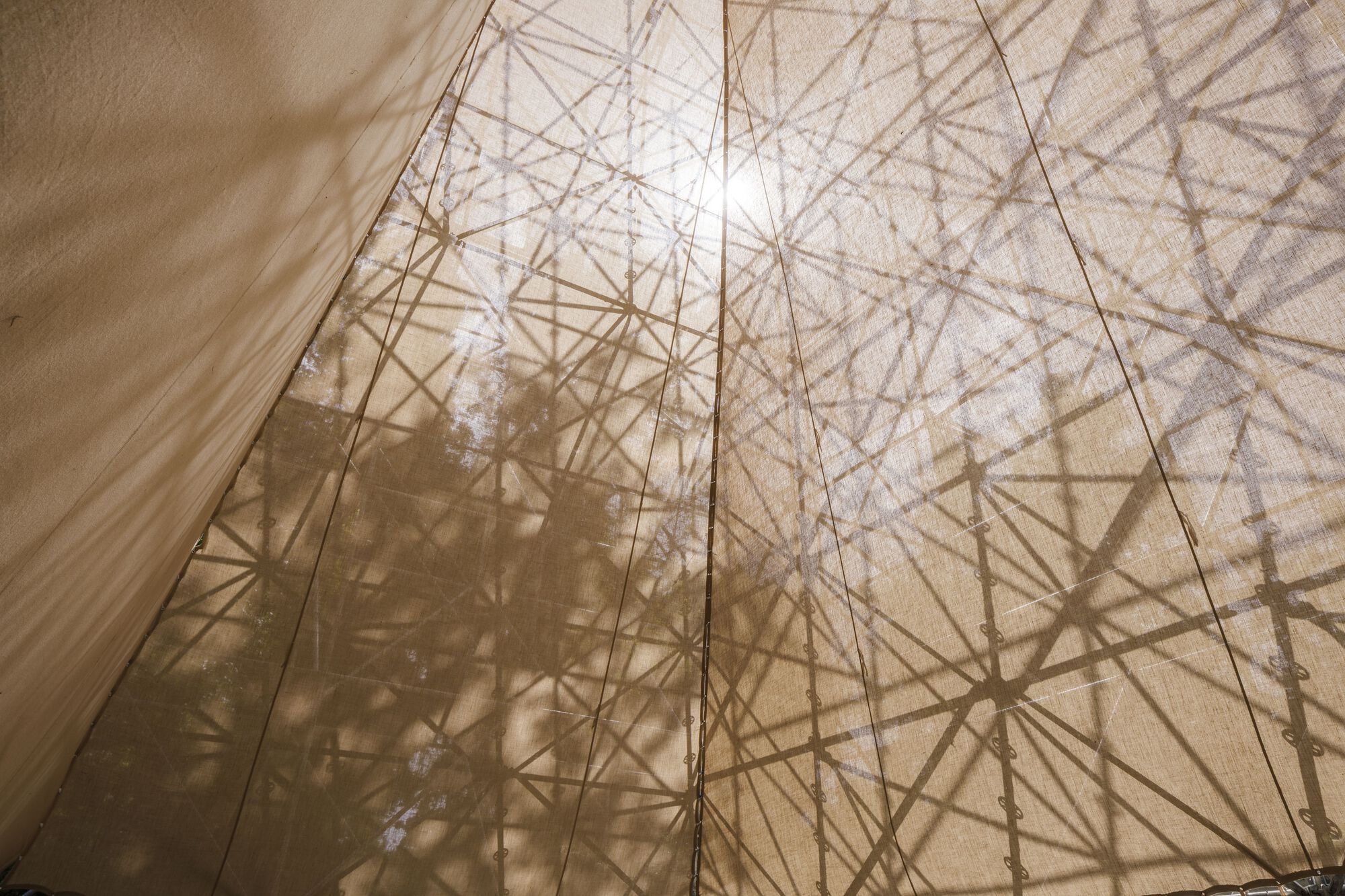 Translucent fabric wall with geometric structural shadows visible through the material in bright sunlight