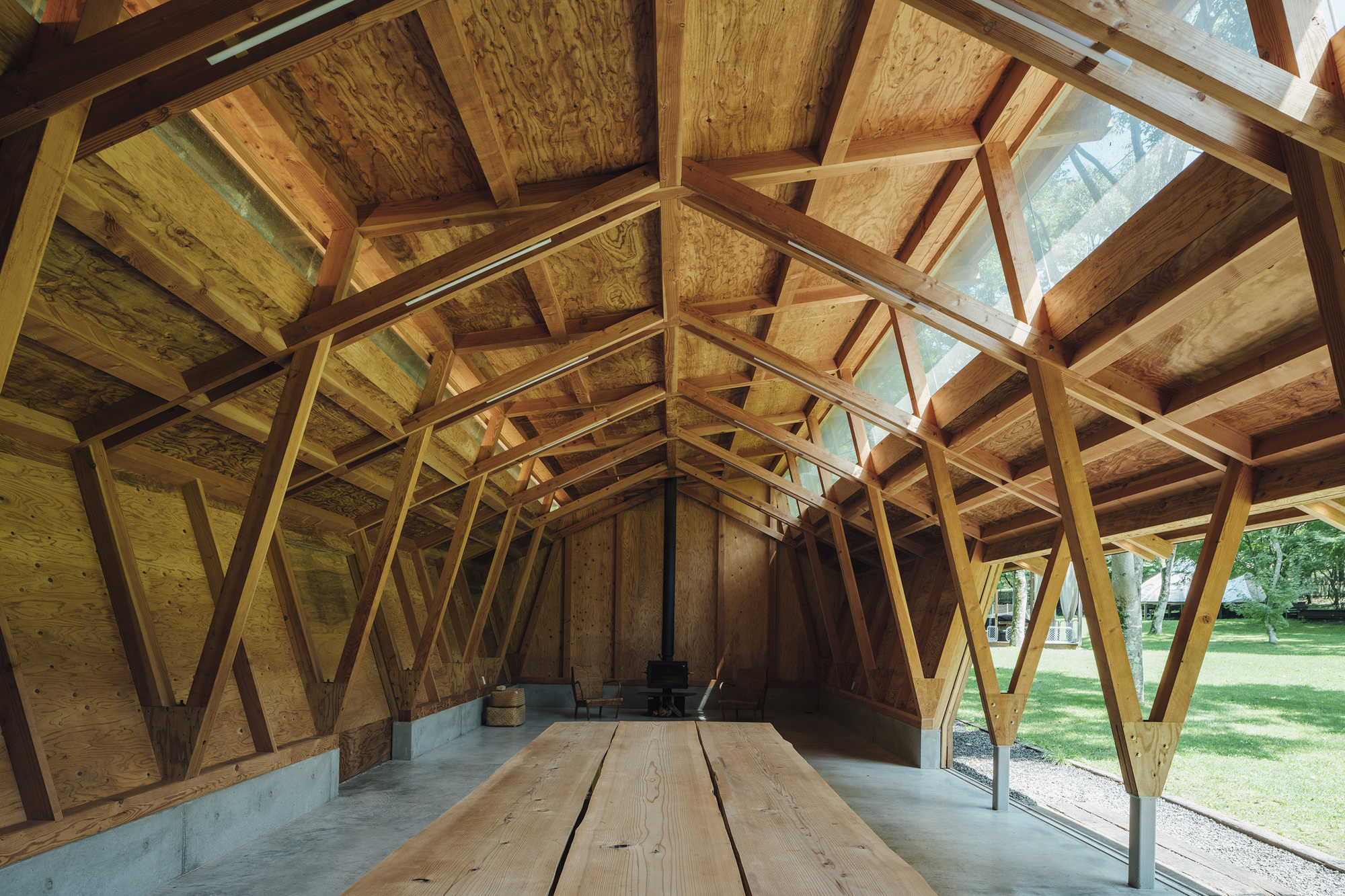 Interior view showing diagonal timber bracing and plywood ceiling panels with clerestory glazing above timber benches