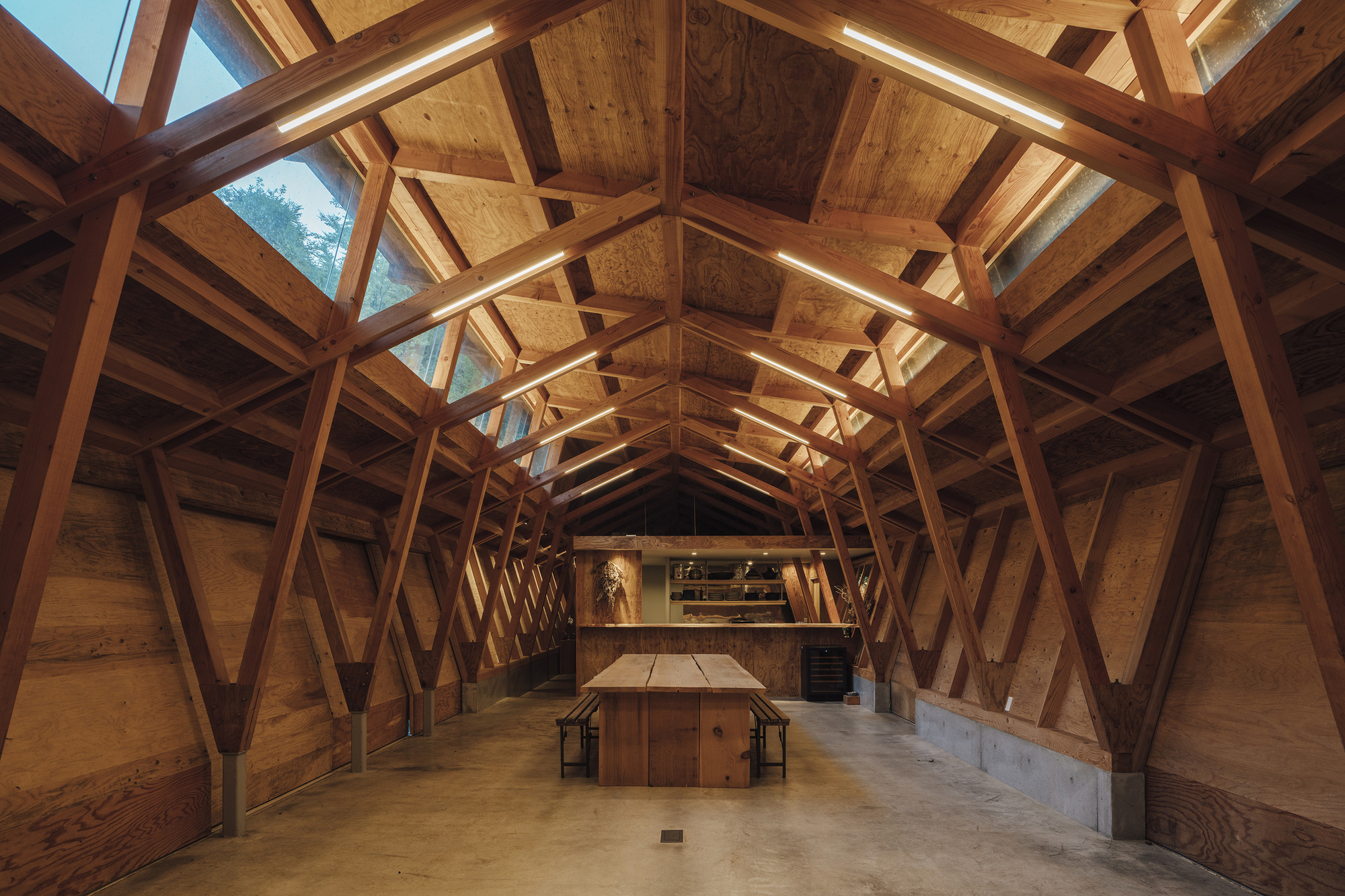 Interior perspective showing repeating diagonal timber frames and ridge skylights above the central gathering space