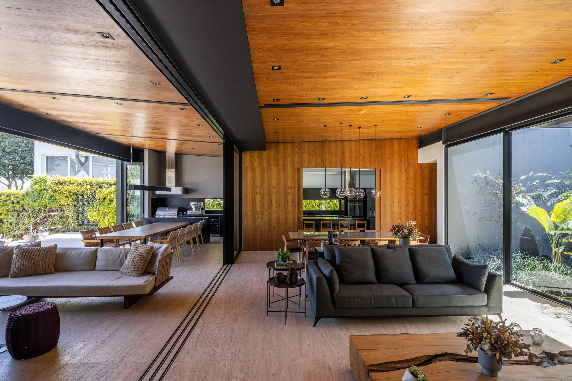Open-plan living space with timber ceiling, steel beams and floor-to-ceiling glazing overlooking garden